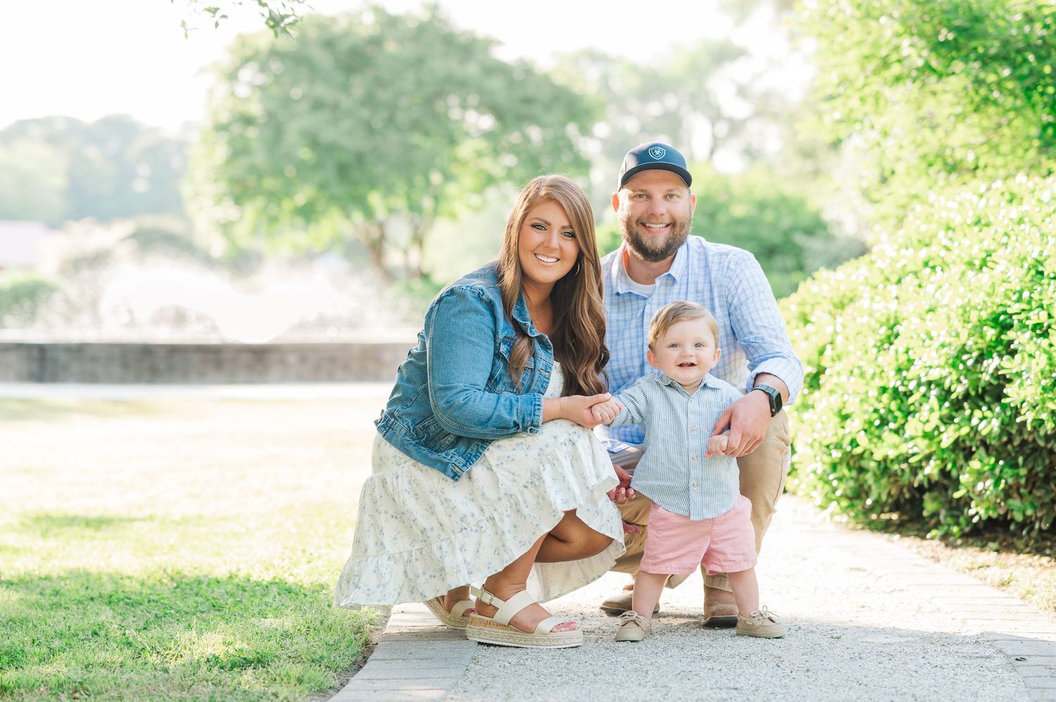 Family portrait session in a lush green garden setting during golden hour.