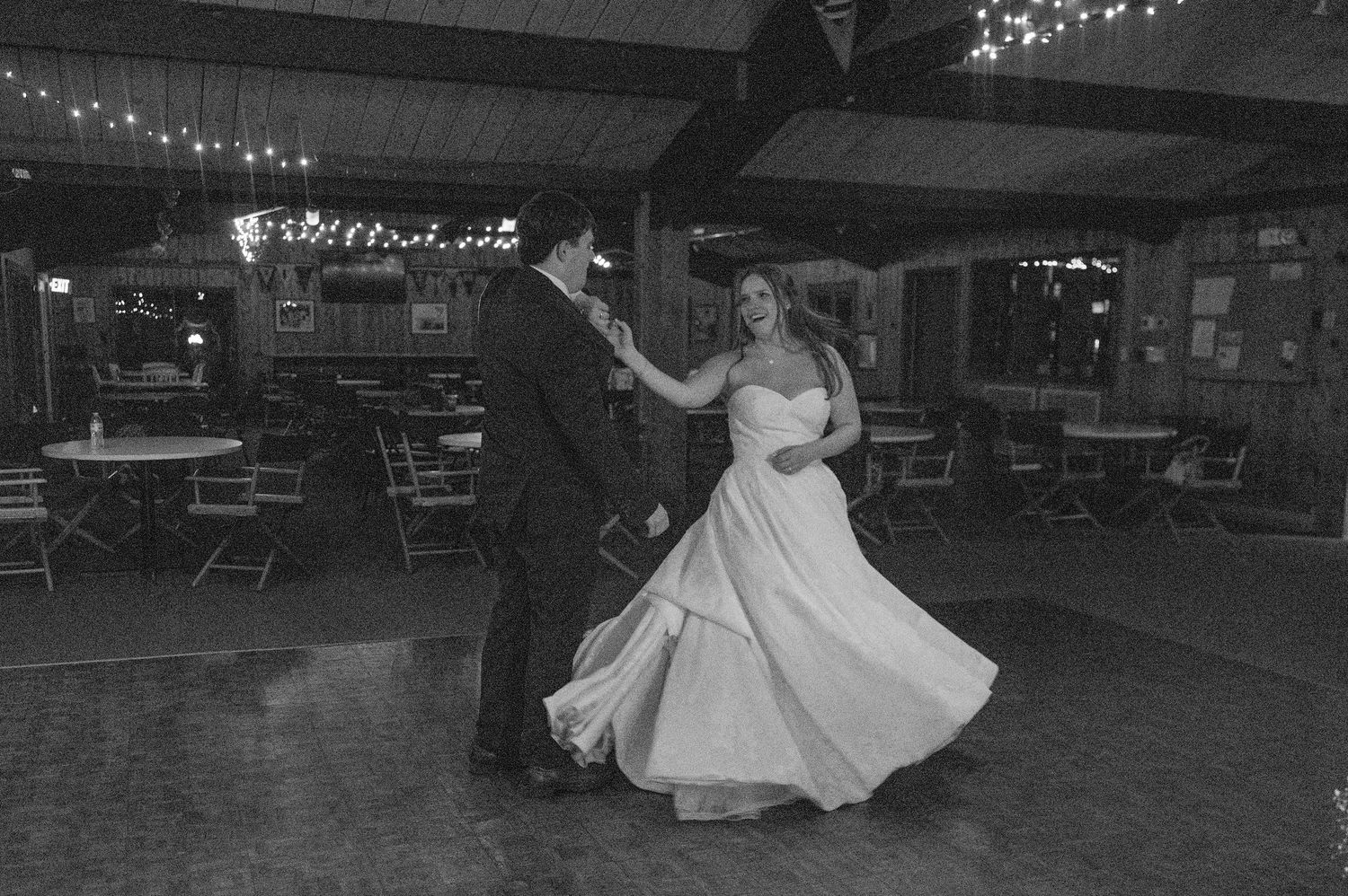 Black and white photo of couple's romantic first dance at dimly lit wedding reception.