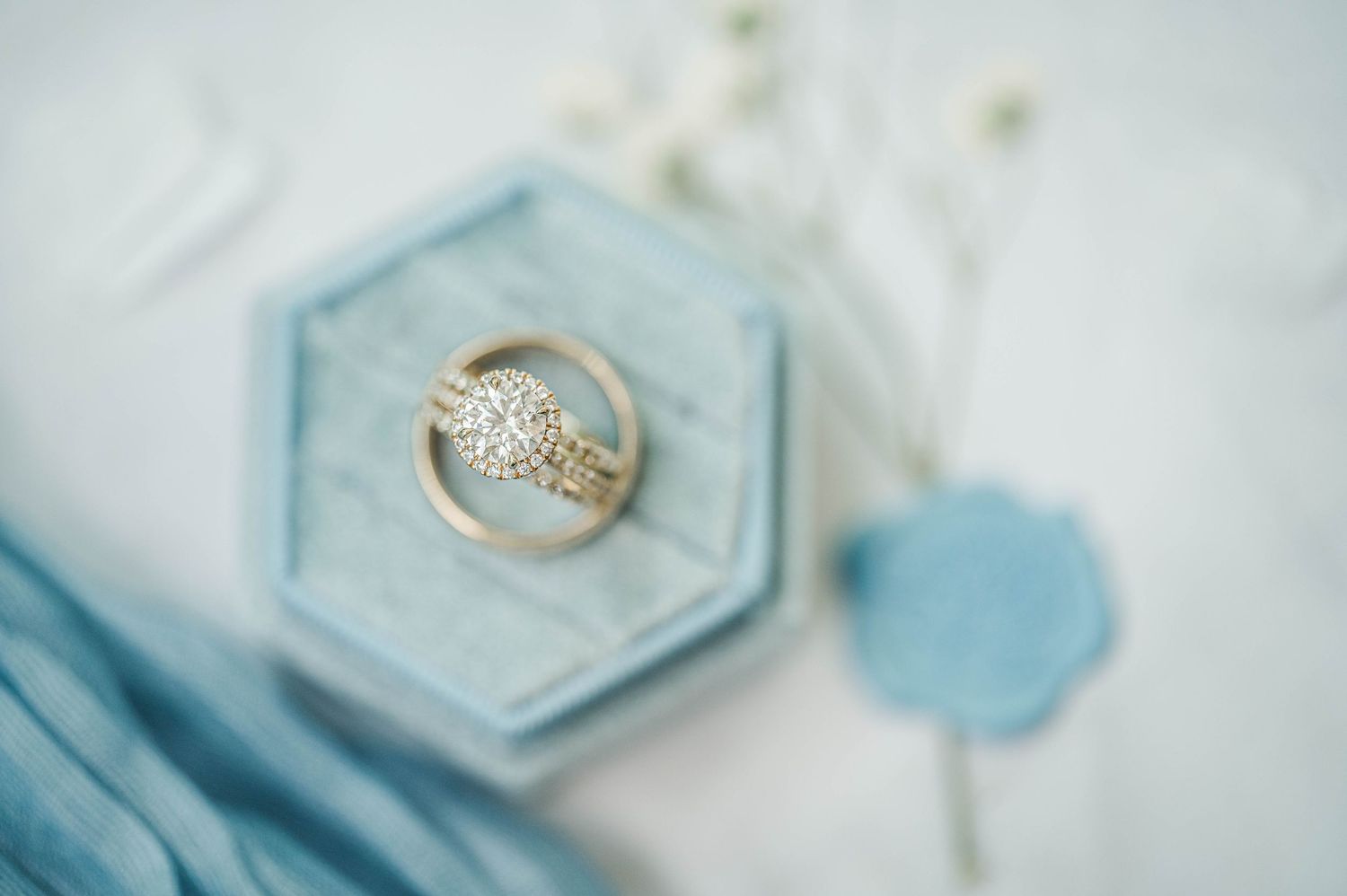 Wedding rings displayed on light blue hexagonal plates with delicate styling.