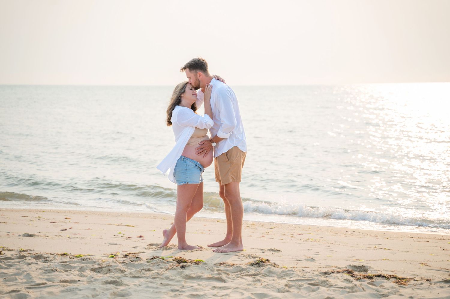 Couple walking and playing together on sandy beach at sunset.