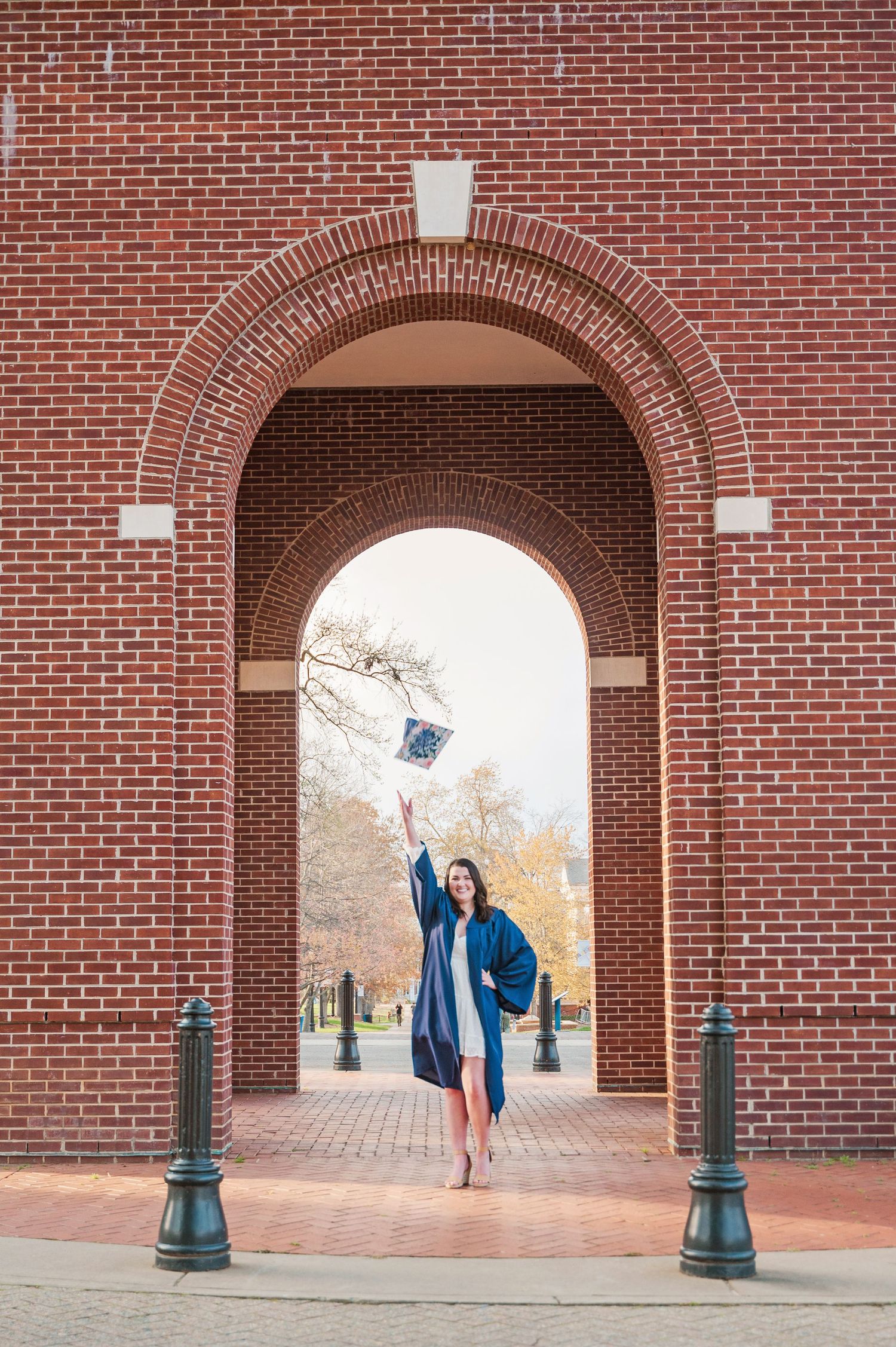 College graduate in cap and gown in the college archway.
