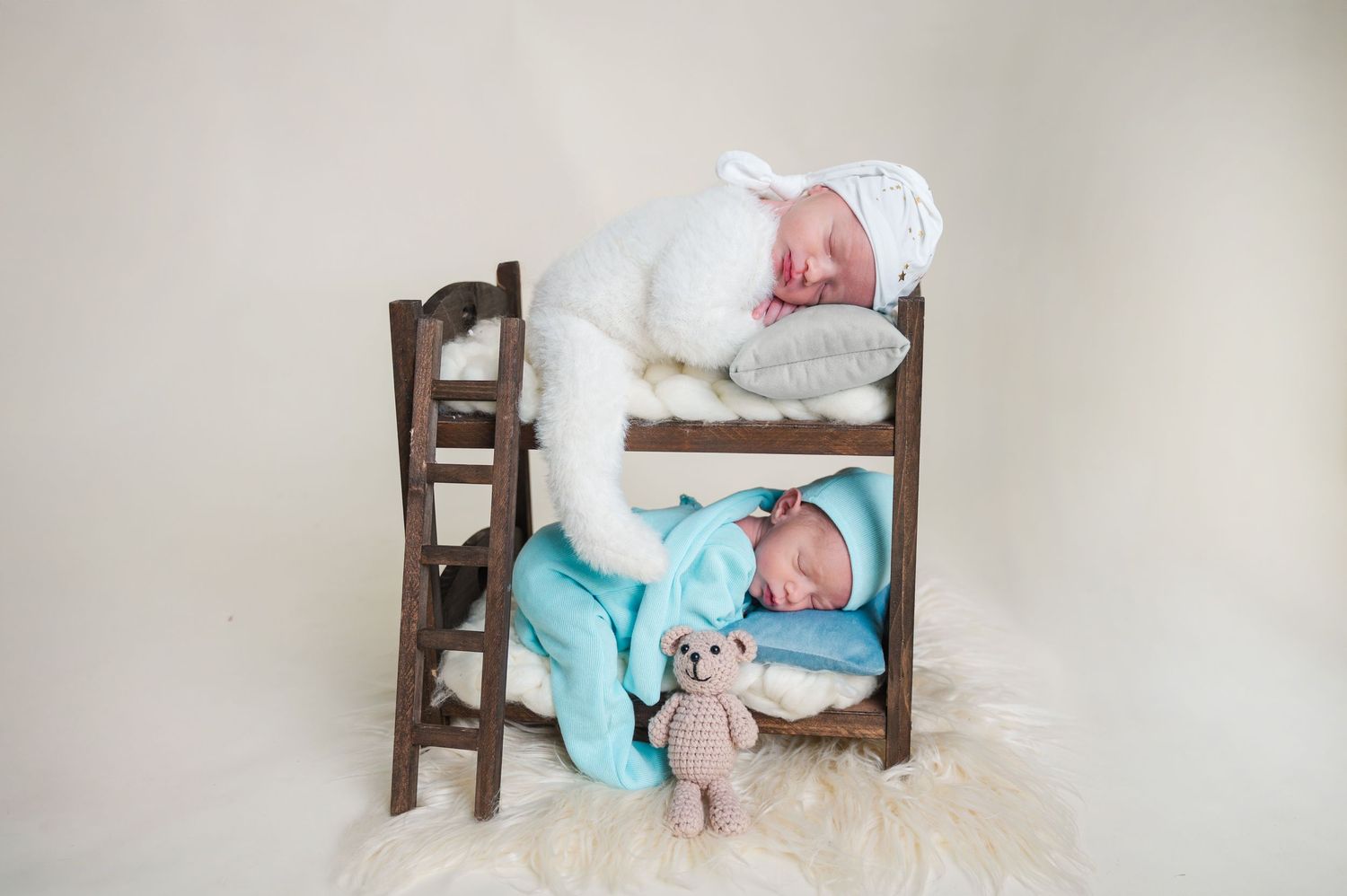 Miniature bed prop setup with tiny teddy bear for newborn photography.