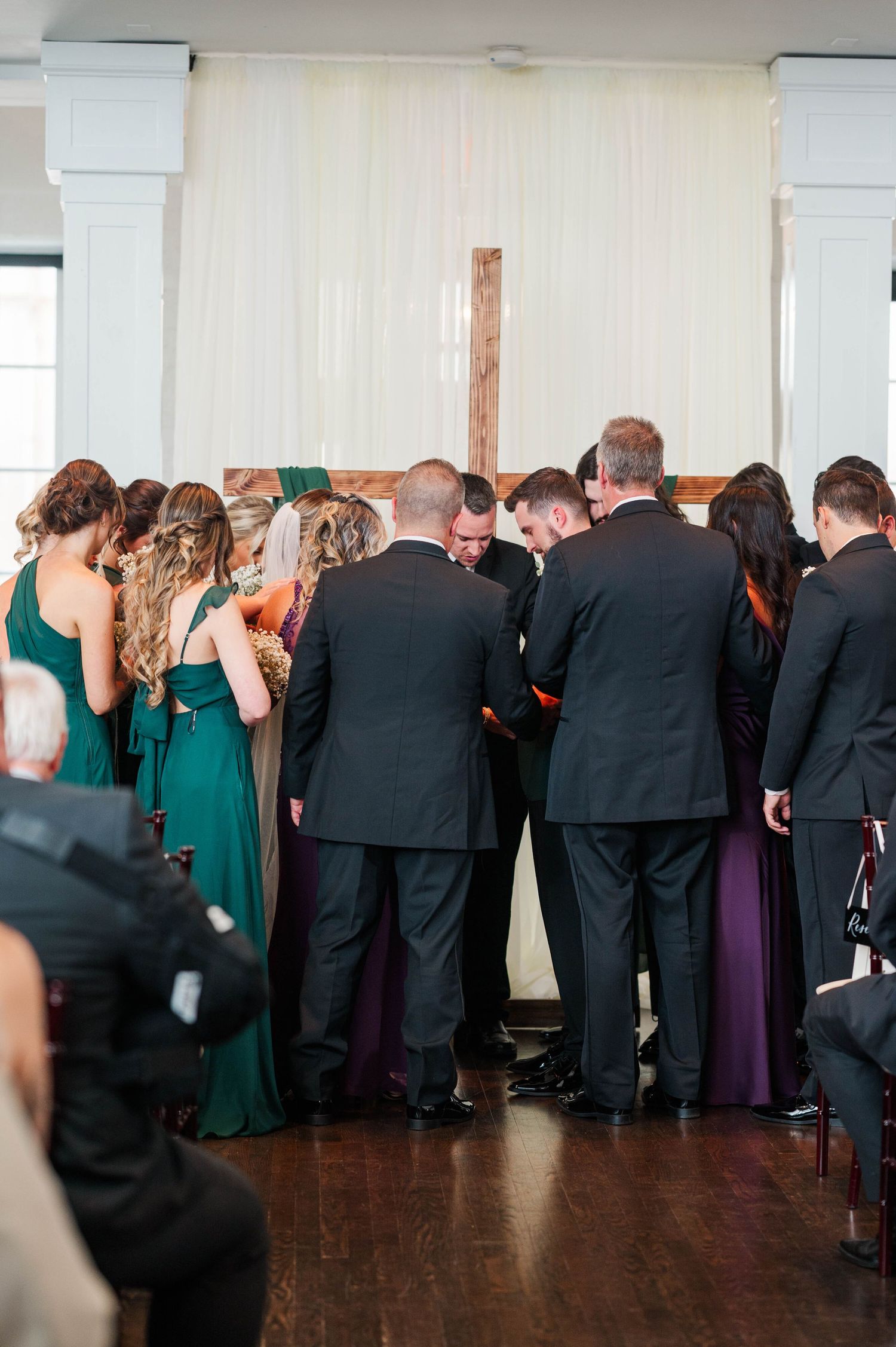 Wedding party lined up in formal attire with emerald green and black outfits.