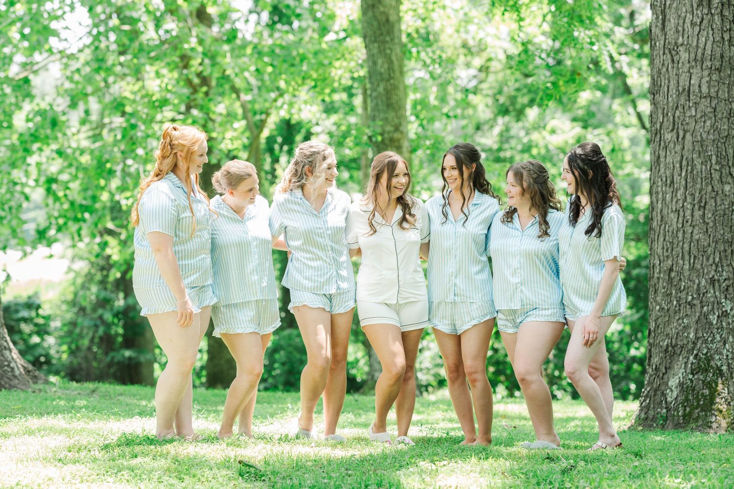 People in coordinated outfits sitting on grass in front of tall trees.