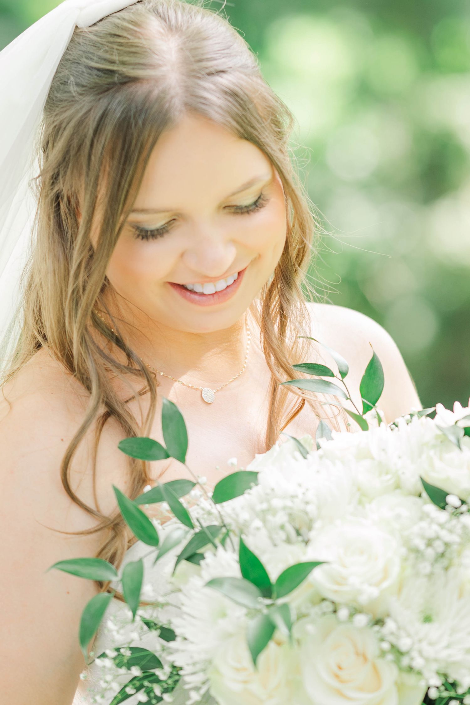 Ethereal bridal portrait with white roses and greenery bouquet in natural lighting.