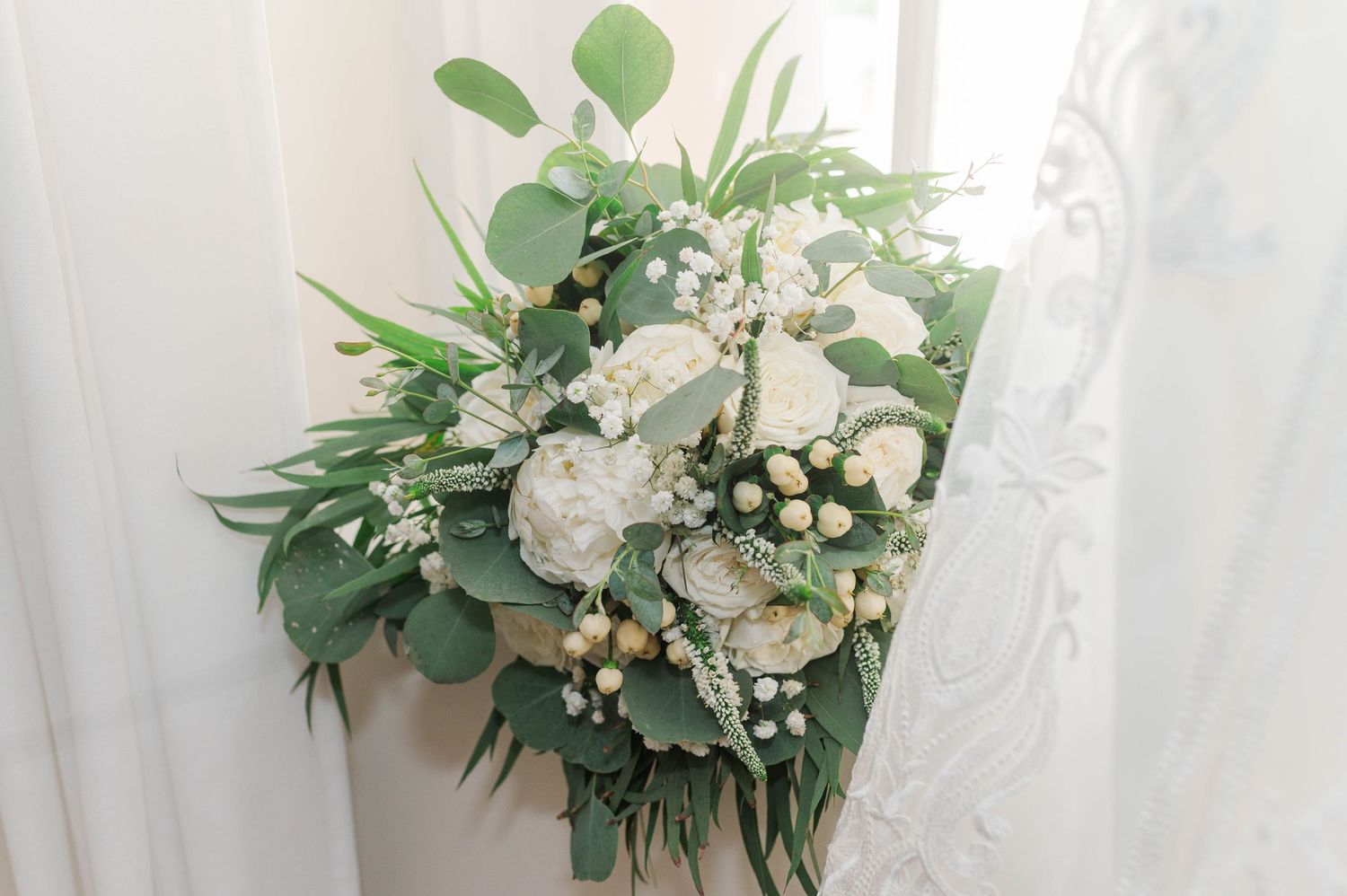 White and green wedding bouquet with roses, eucalyptus and delicate florals.