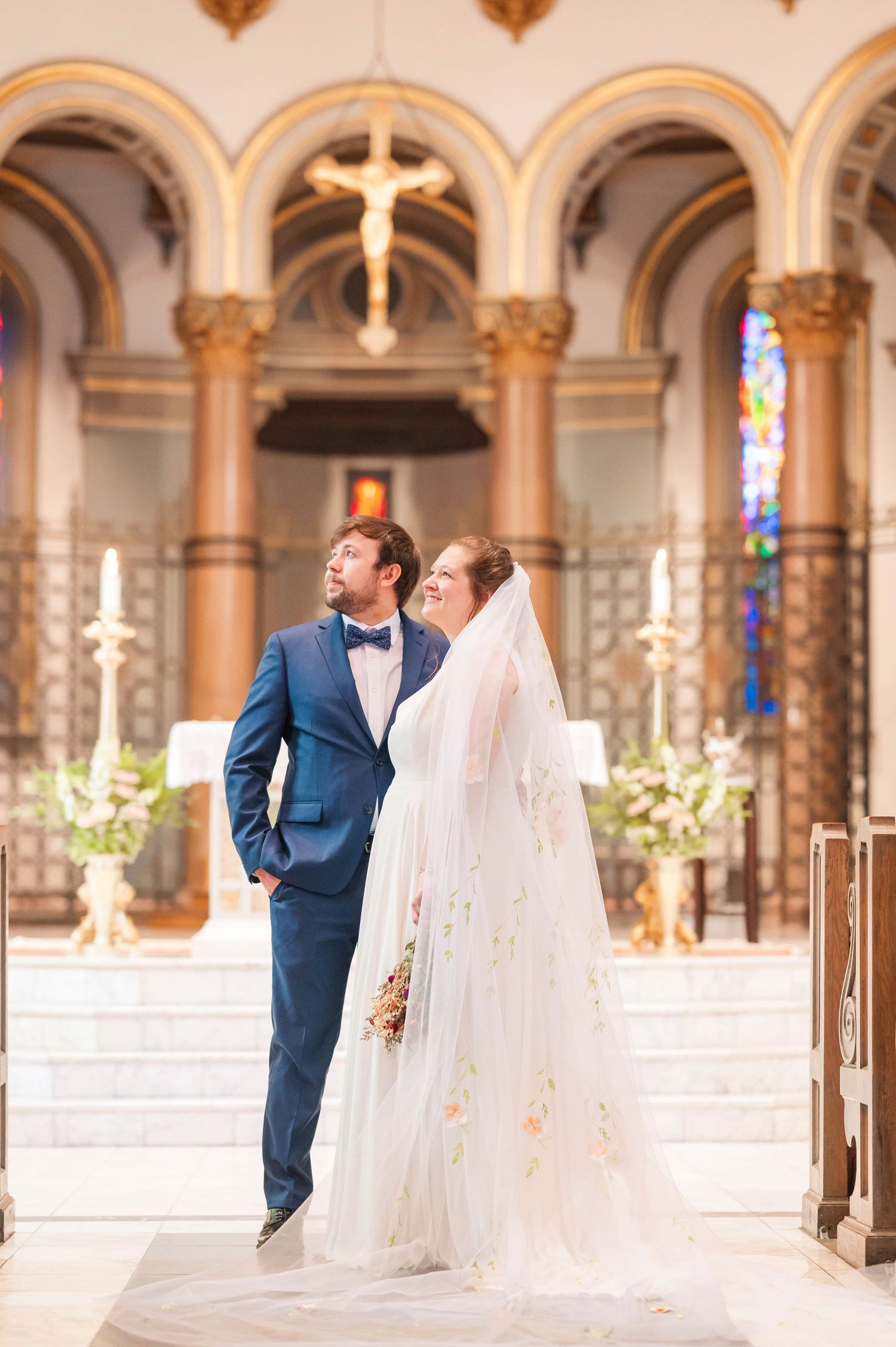 Elegant church wedding ceremony with ornate arches and stained glass windows in the background.