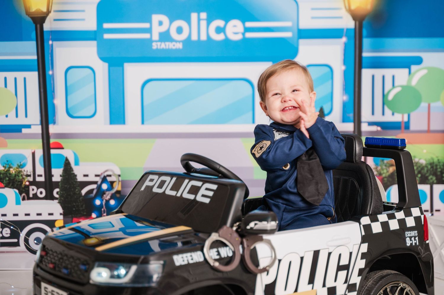 Police themed party backdrop with toy cars and decorative elements against a blue background.