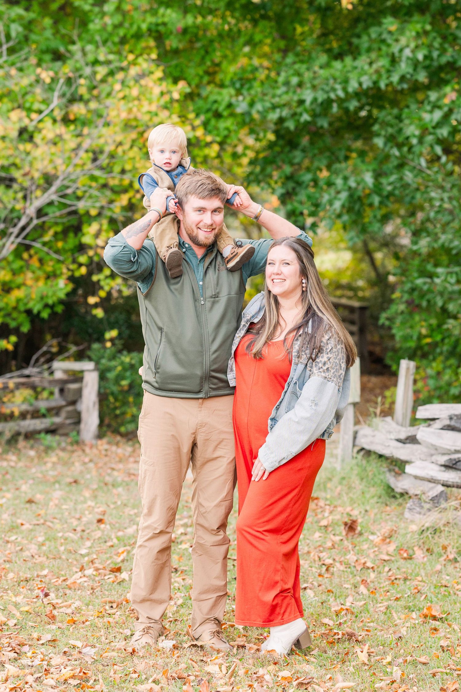 Family enjoying autumn day among fallen leaves in park setting.