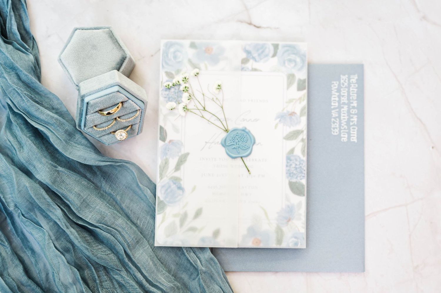 Elegant wedding stationery flat lay with blue silk ribbon and delicate floral designs.