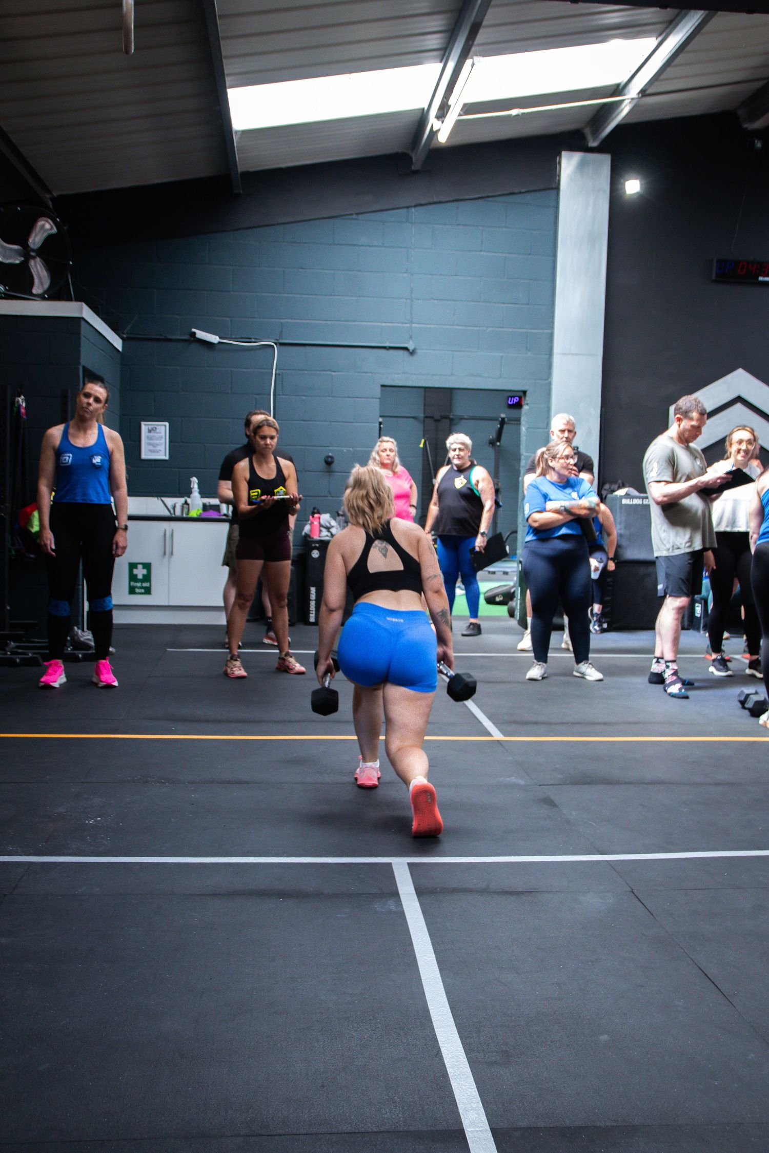 People exercising in a gym with blue walls during a group fitness class on a dark rubber floor.