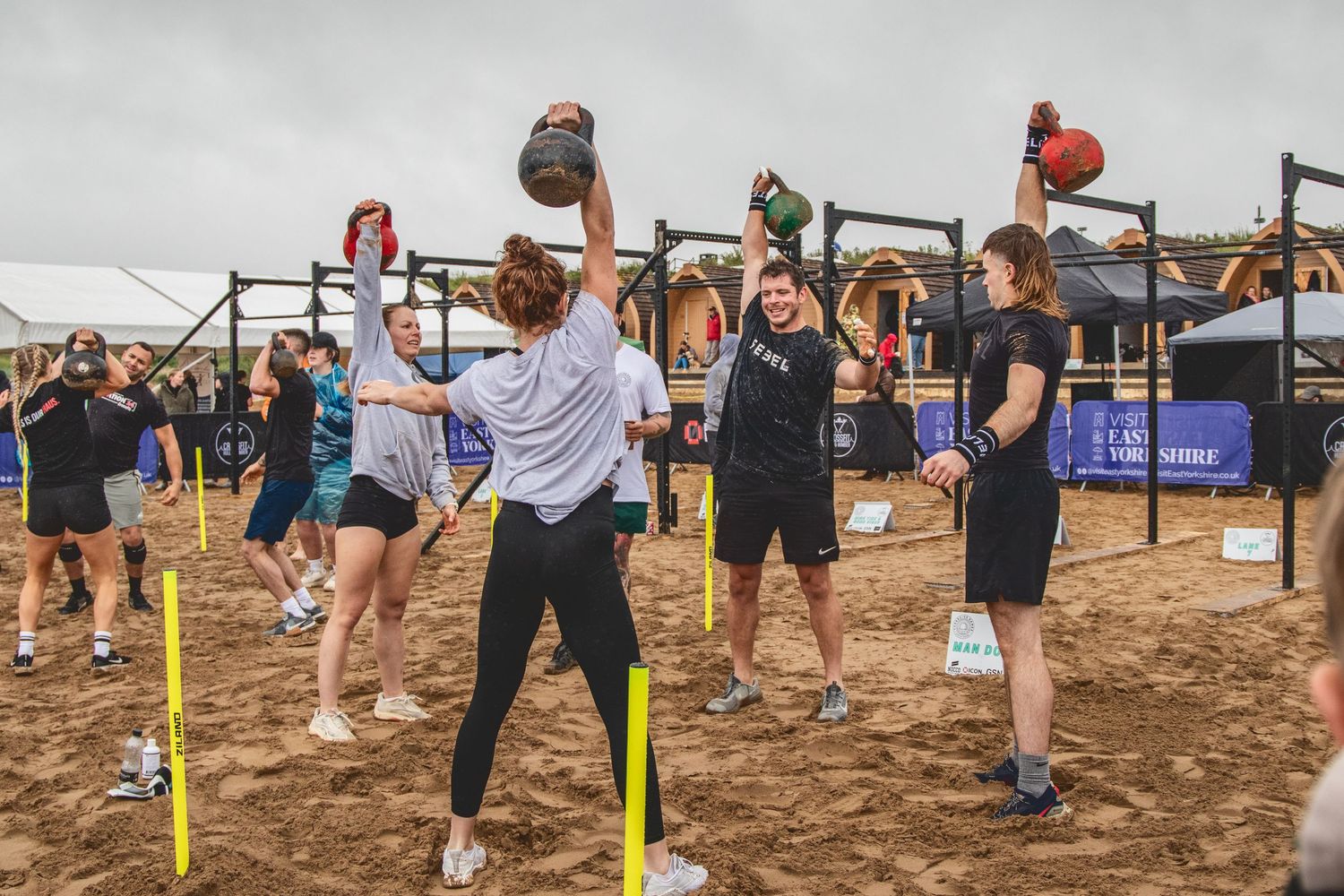 Group of athletes training with medicine balls at an outdoor sandy fitness facility during an organized workout session.