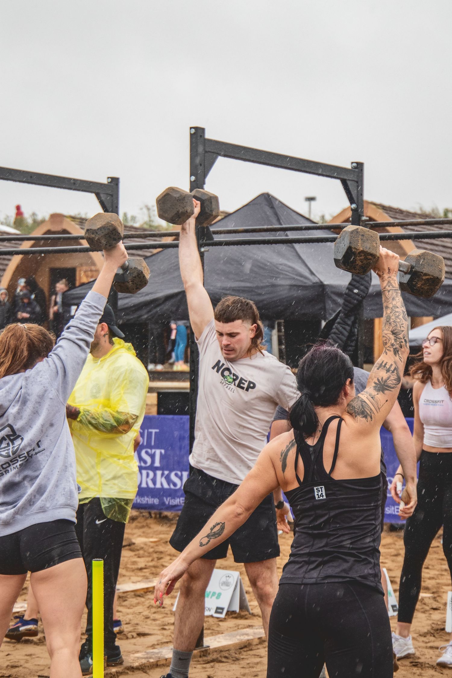 Group of fitness enthusiasts celebrating during an outdoor workout competition with pull-up bars and training equipment.