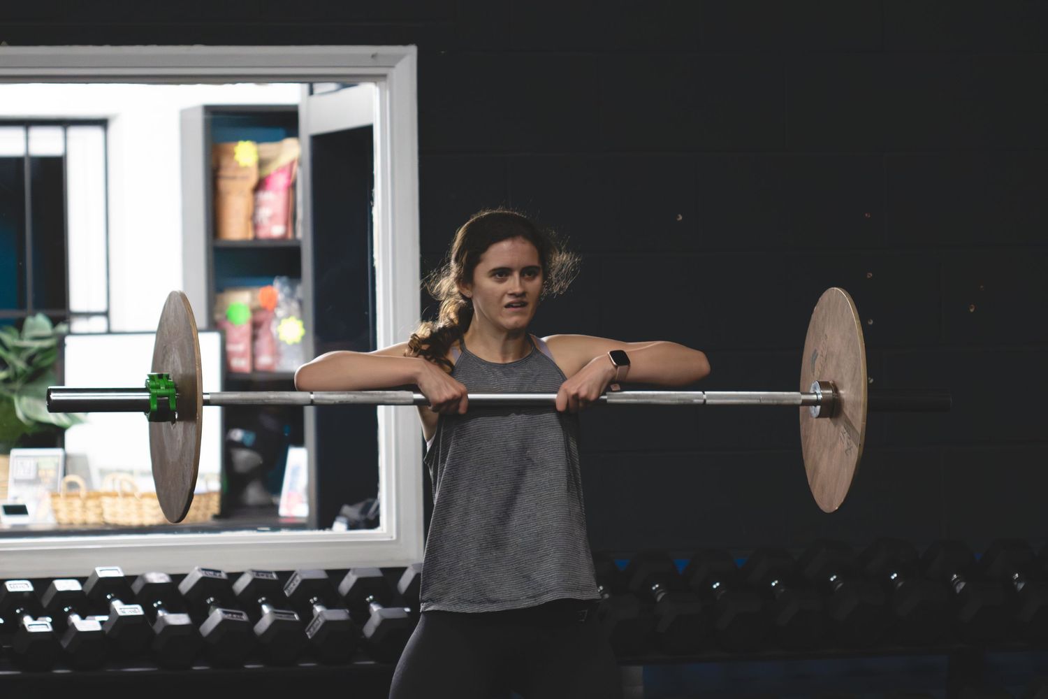 A dark indoor gym space with workout equipment and exercise equipment visible against a black wall.