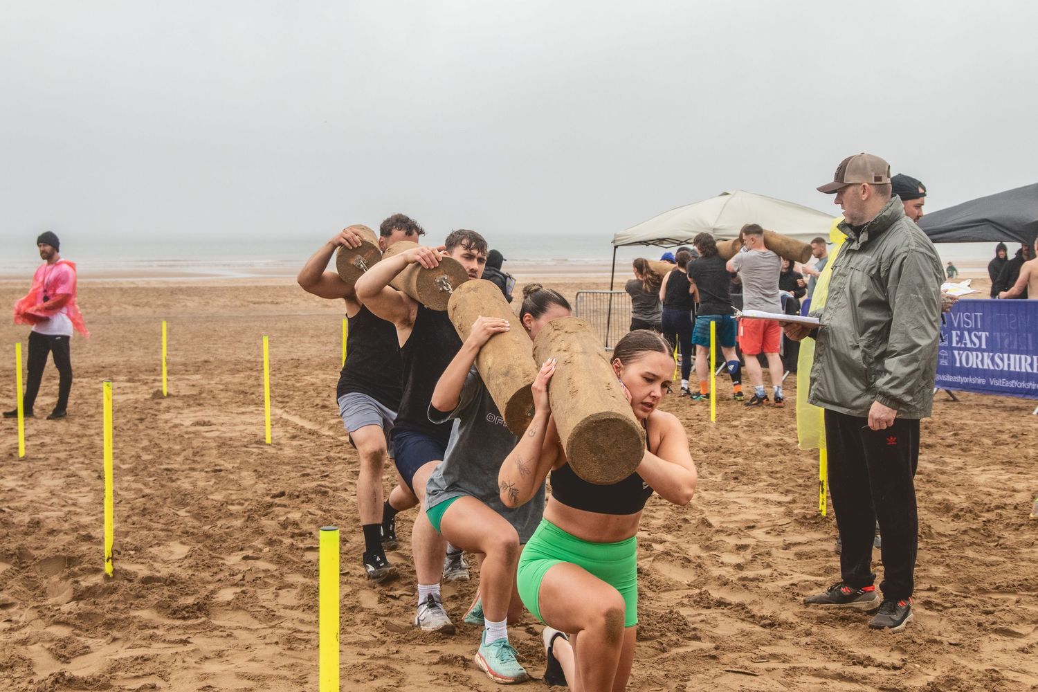 People play volleyball on an outdoor beach court during a casual tournament or gathering.