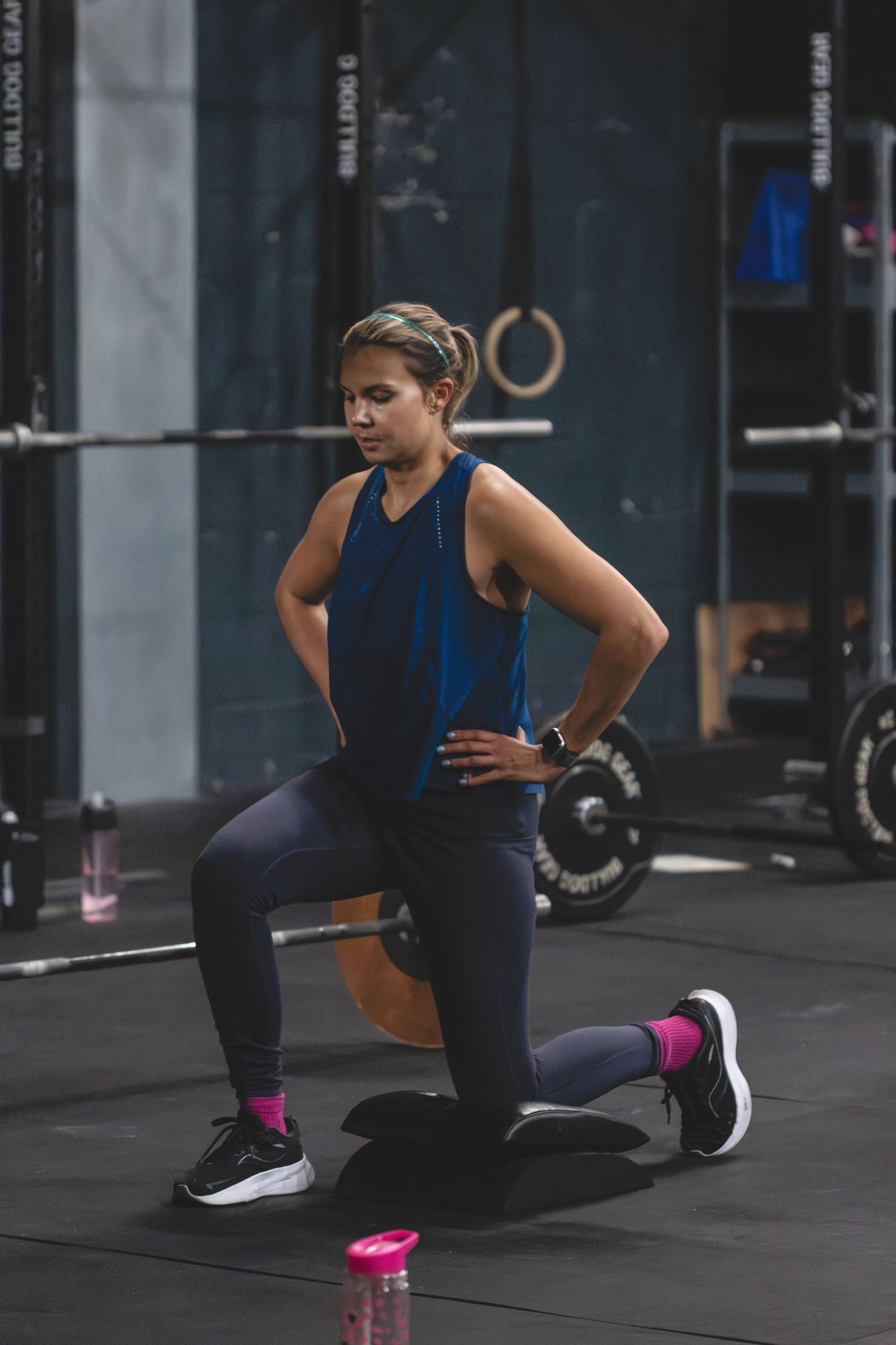 Athlete doing lunges during an intense workout session in a dark gym with weight equipment in the background.