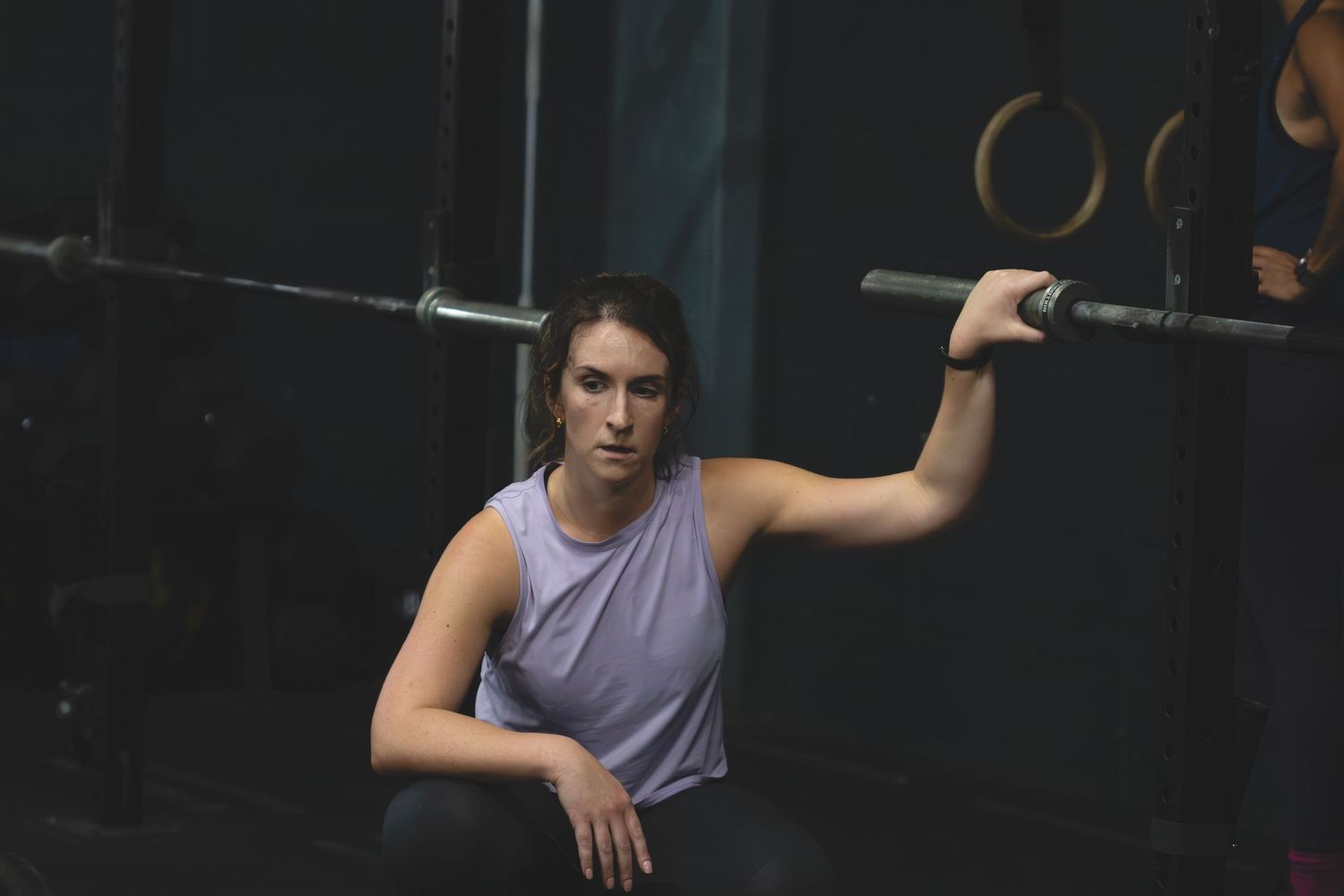 Person performing pull-ups at a gym using gymnastics rings mounted to the ceiling.