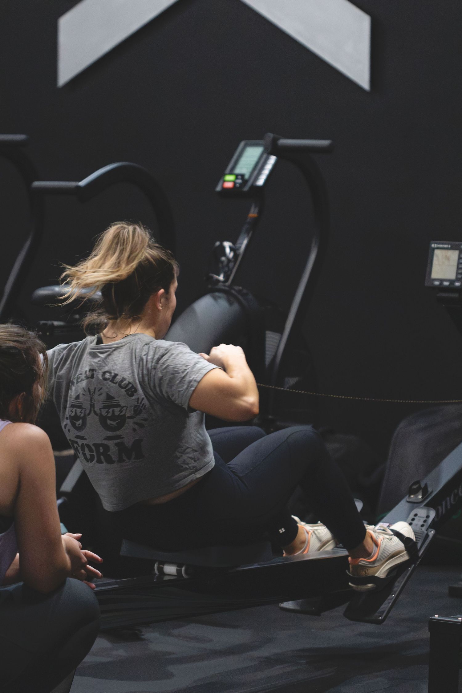 Person wearing grey t-shirt performing back extensions on a gym machine in dark fitness environment.