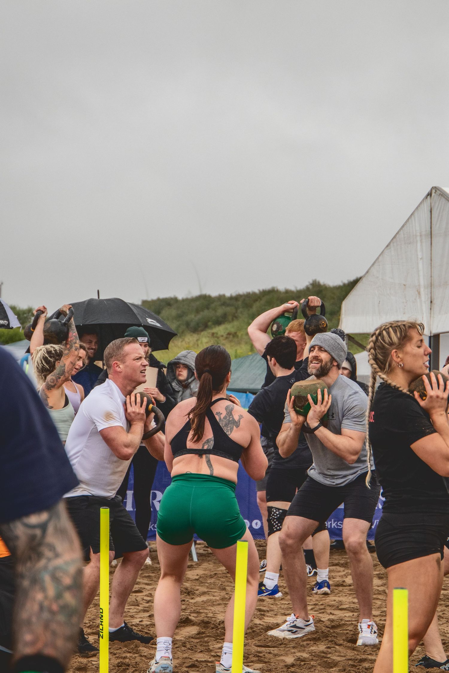 Athletes perform burpees together during an outdoor group fitness competition on a cloudy day.