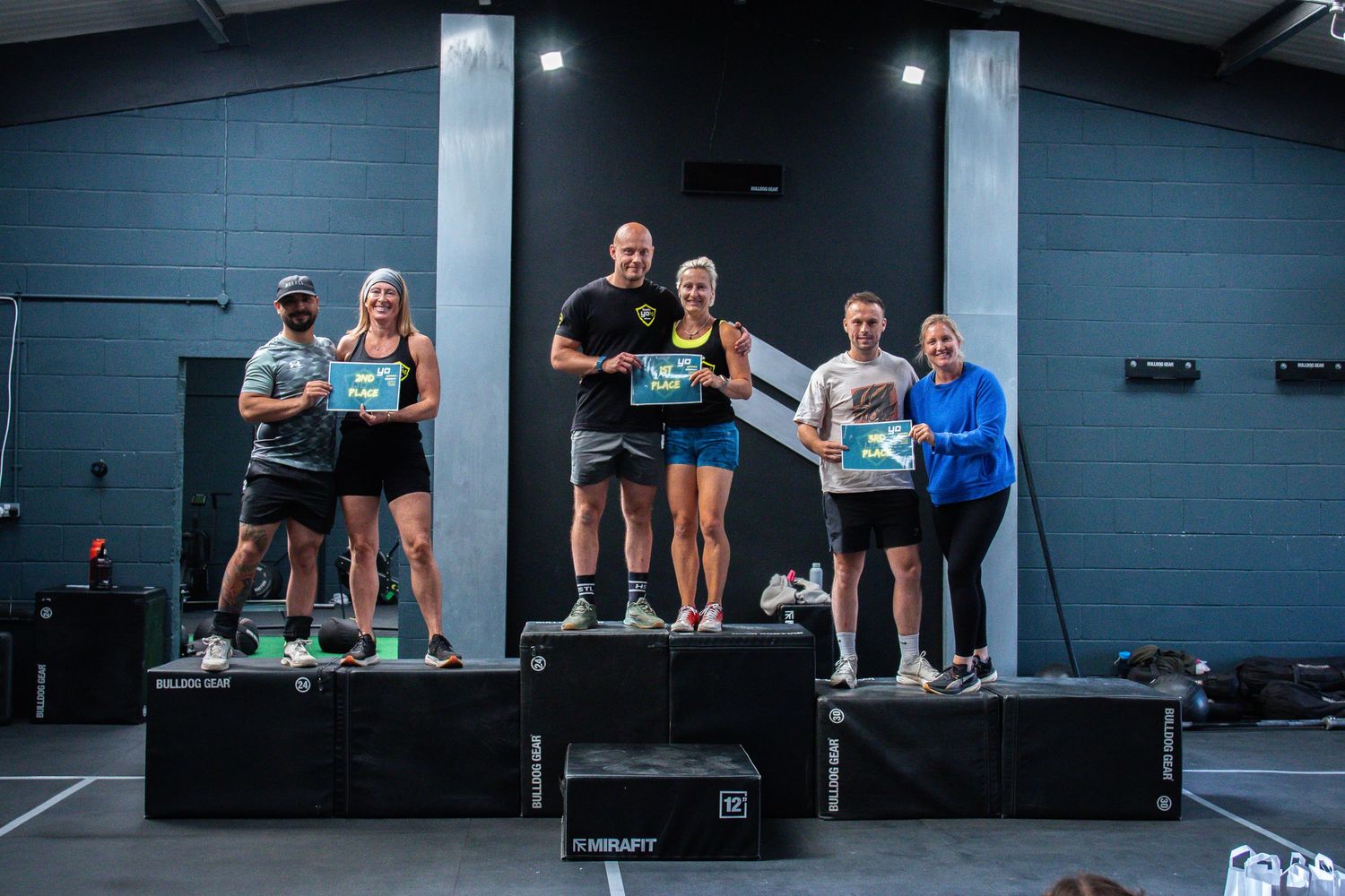 Athletes stand on workout platforms in a crossfit gym celebrating after a training session.