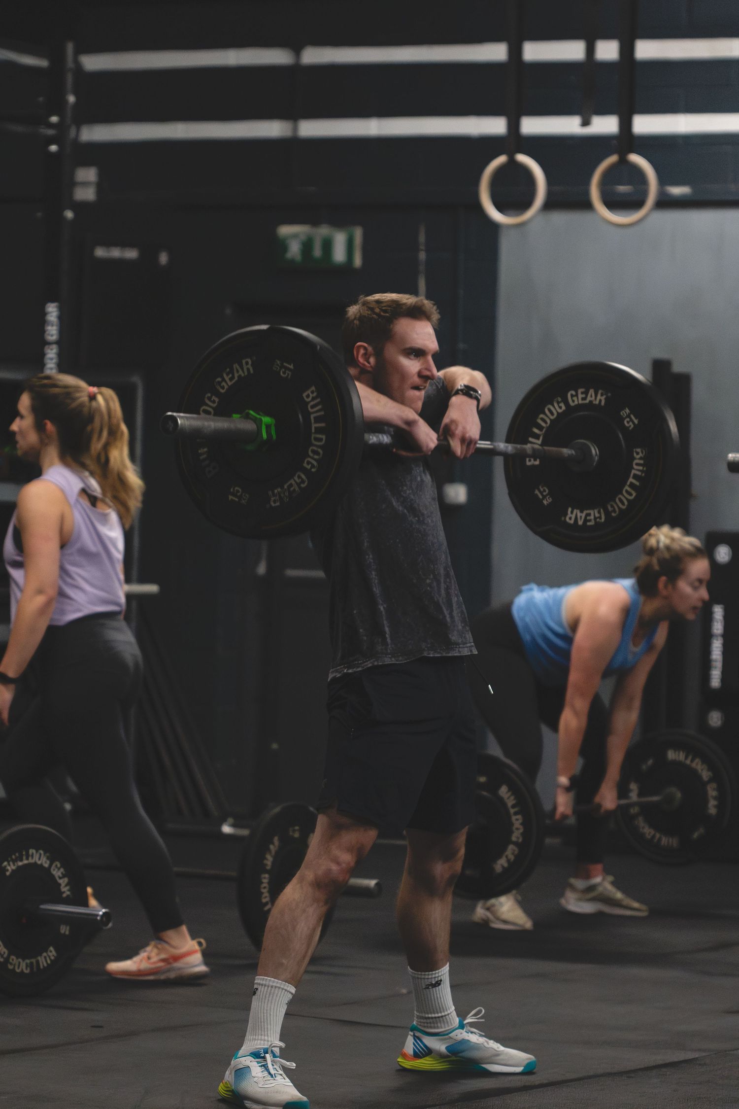 Athletes performing deadlifts with barbells during a CrossFit workout in a dark gym setting.