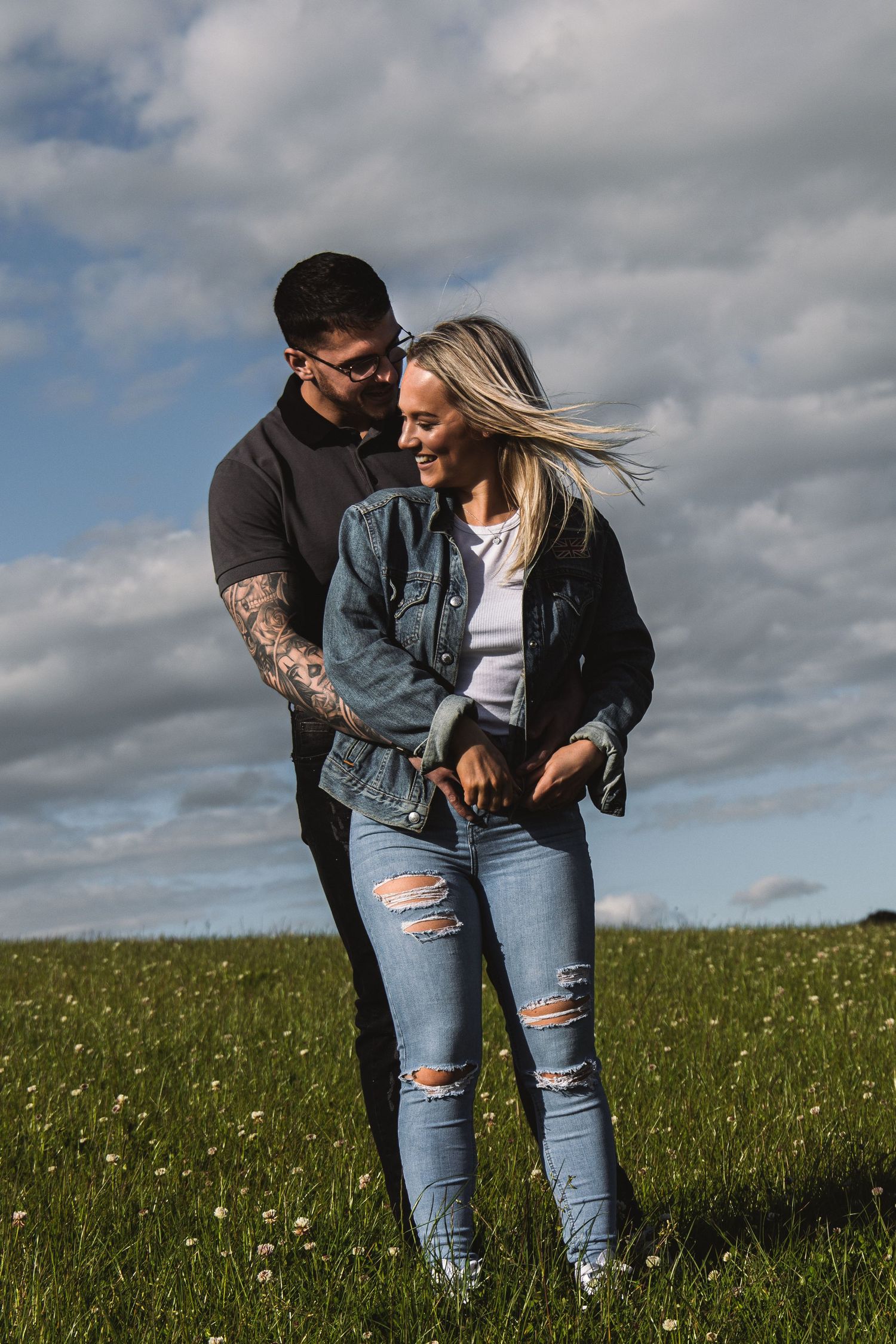 Romantic moment in a windy meadow with clouds overhead.