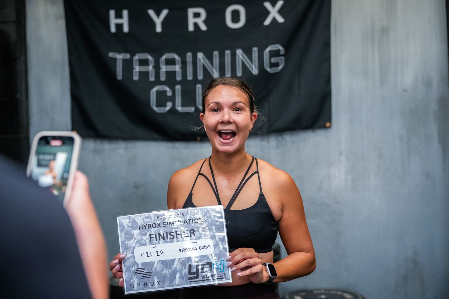 Athletes train in a modern gym facility with Hyrox branding visible on the wall.