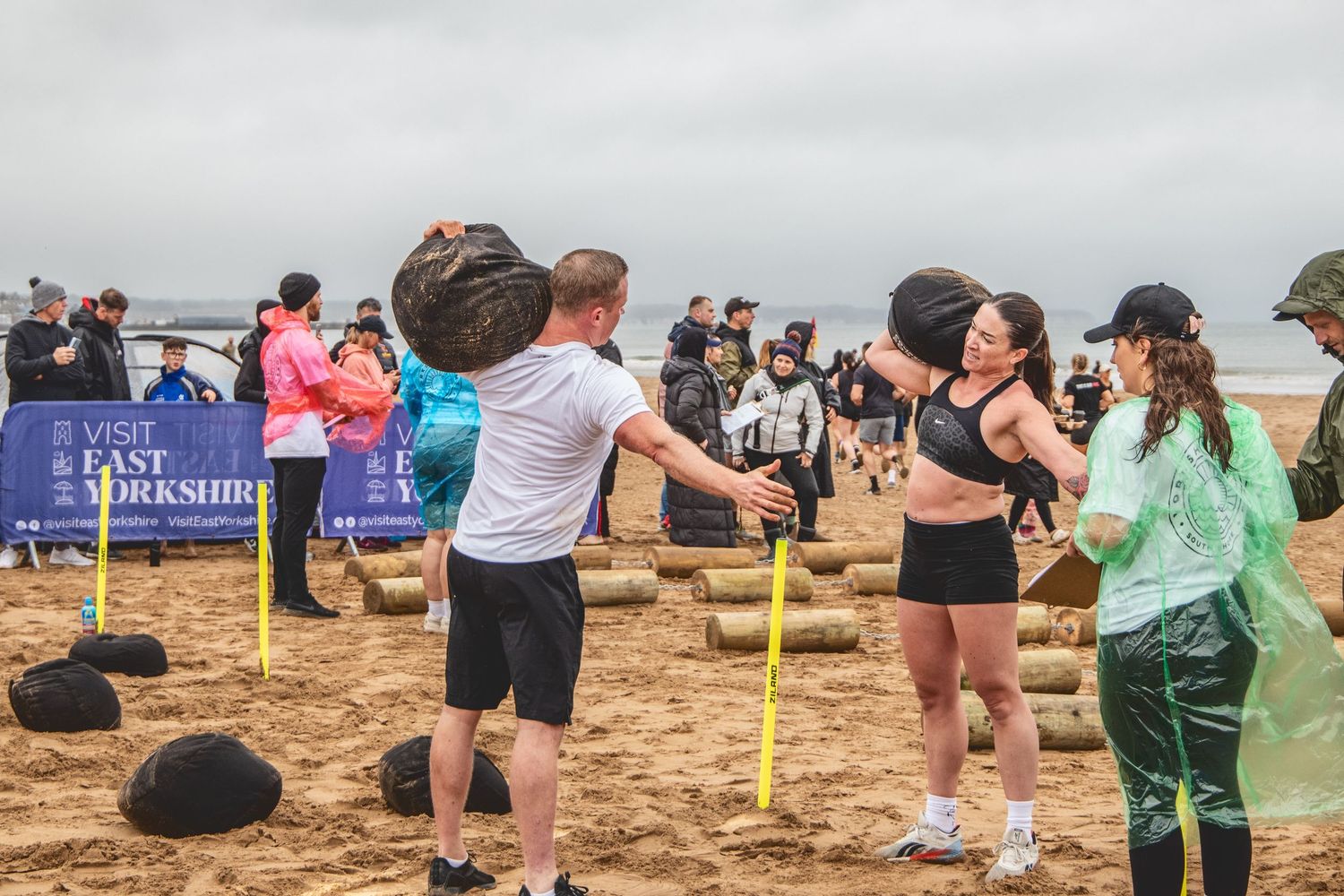 People playing volleyball on a sandy beach court during an outdoor tournament or competition.