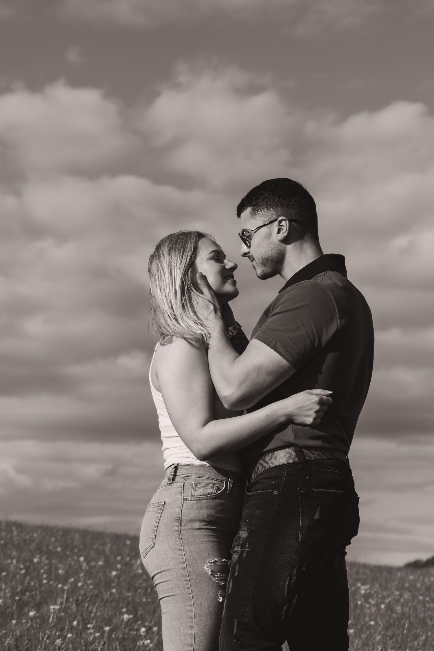 Black and white portrait of a couple's intimate moment in a wildflower field.