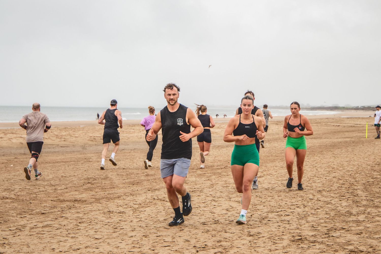 Group of runners participating in a marathon or training event on a dry, dusty terrain under an overcast sky.
