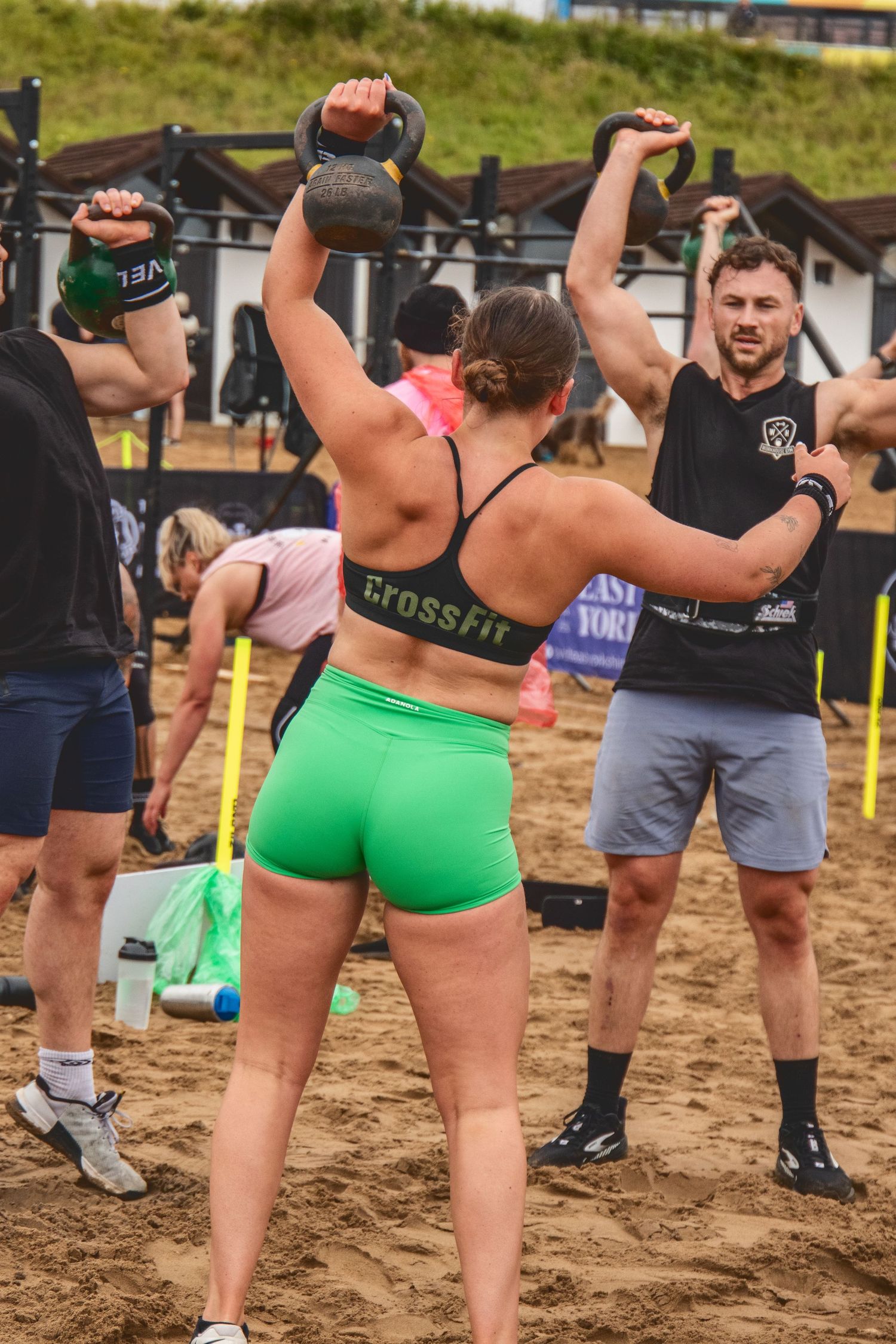 A sequence of fitness enthusiasts performing exercise movements together outdoors on sandy terrain.