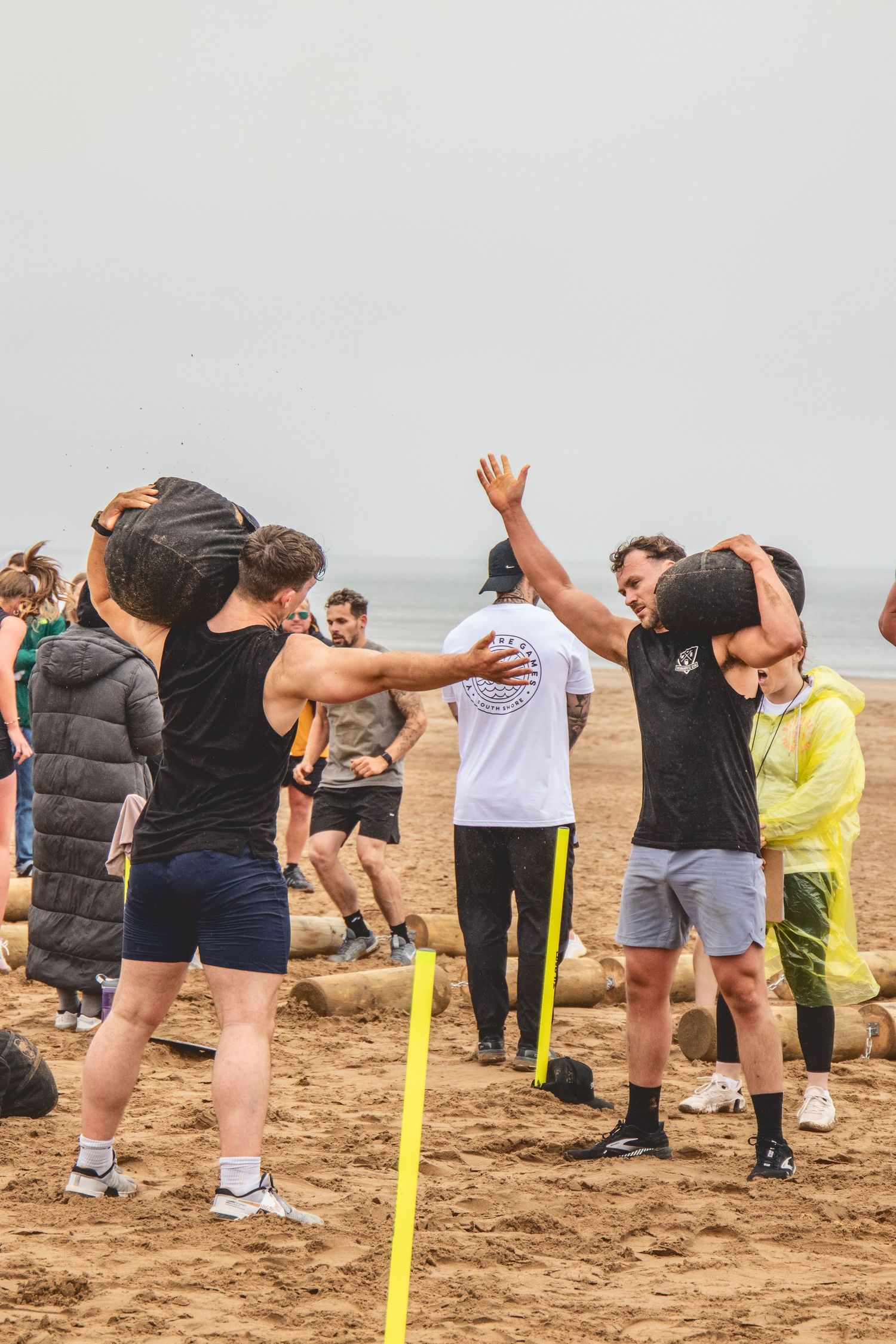 A group stretches on a sandy beach while following a dance or exercise routine.
