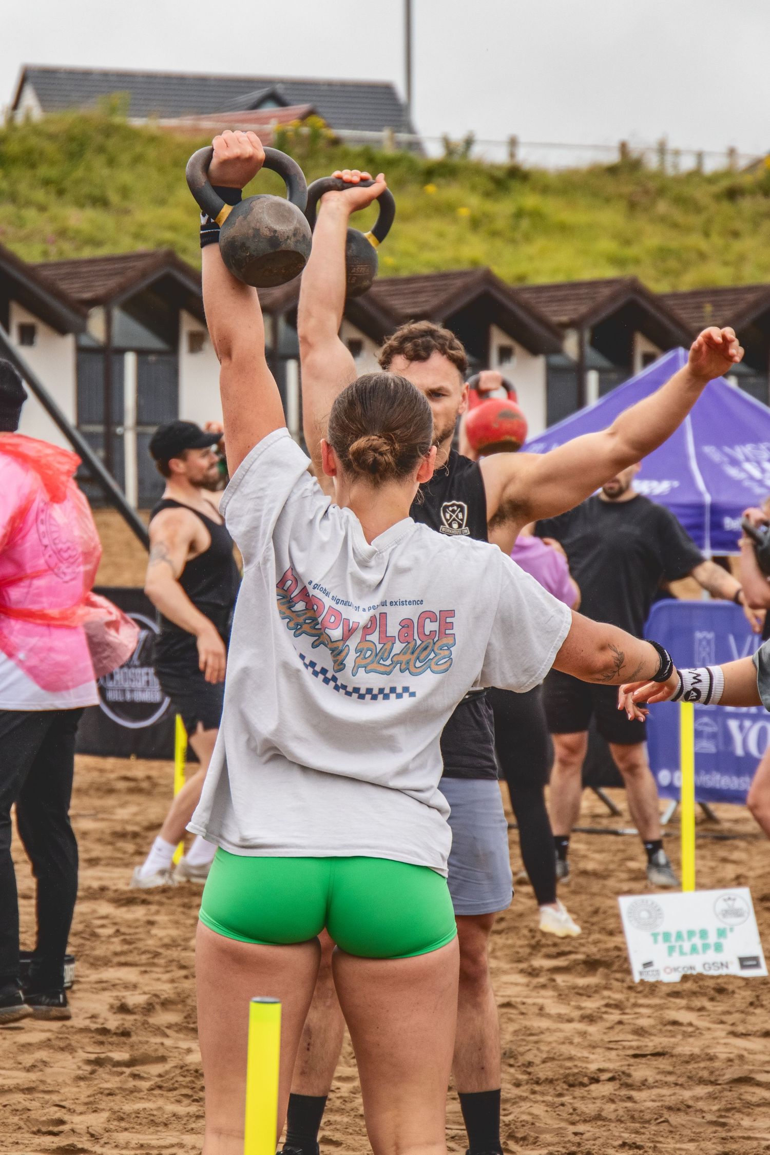 A group of participants stretch and warm up on a sandy beach before an outdoor fitness event.