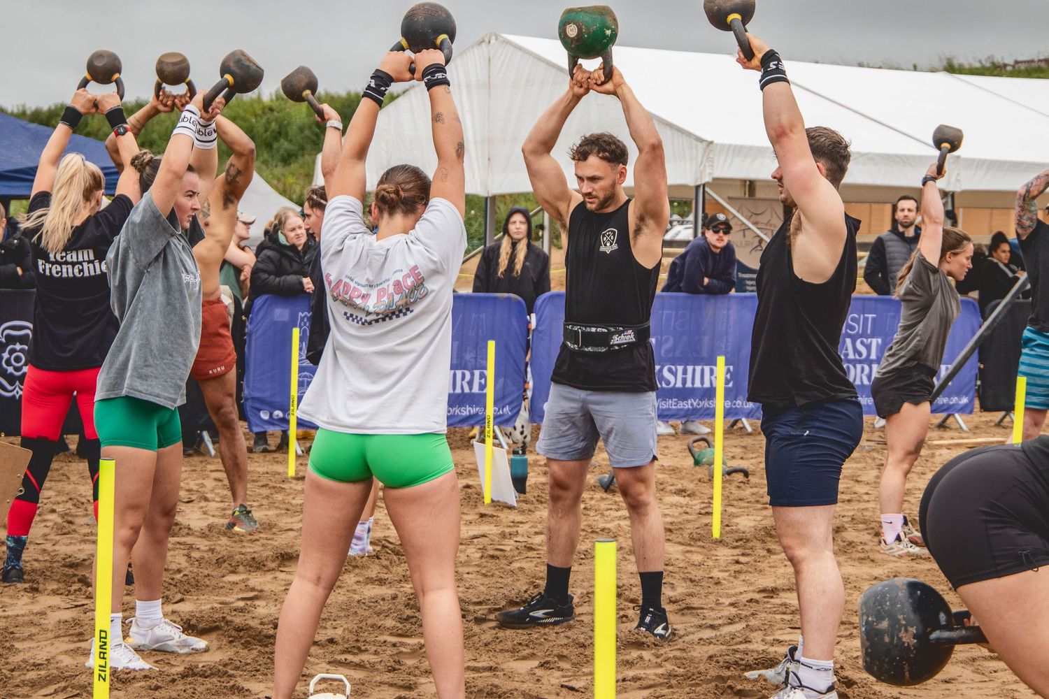 Outdoor volleyball players on a sand court jumping and hitting the ball during a beach tournament match.