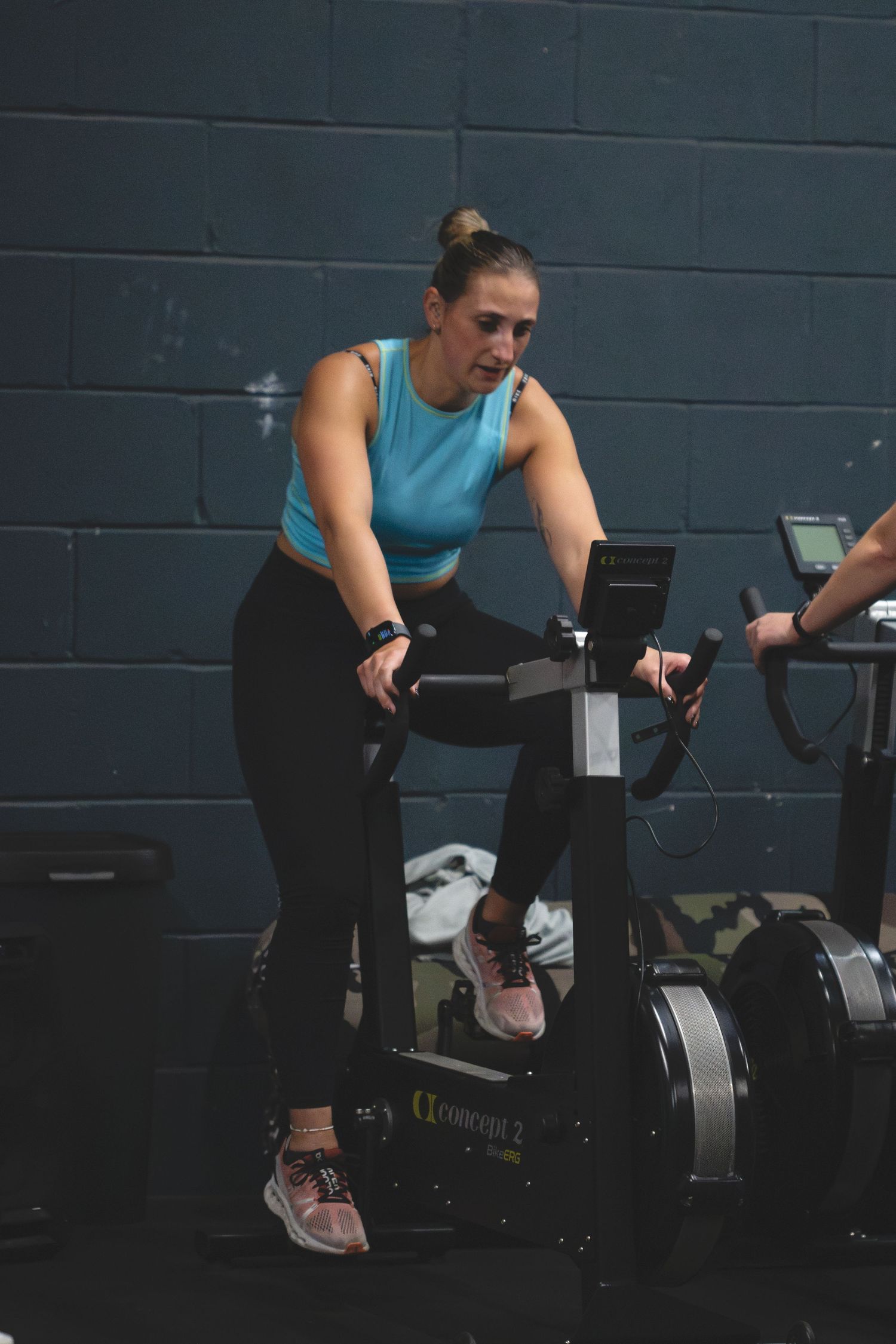 Sequence showing someone performing a cycling workout on a stationary exercise bike in a dark gym environment.