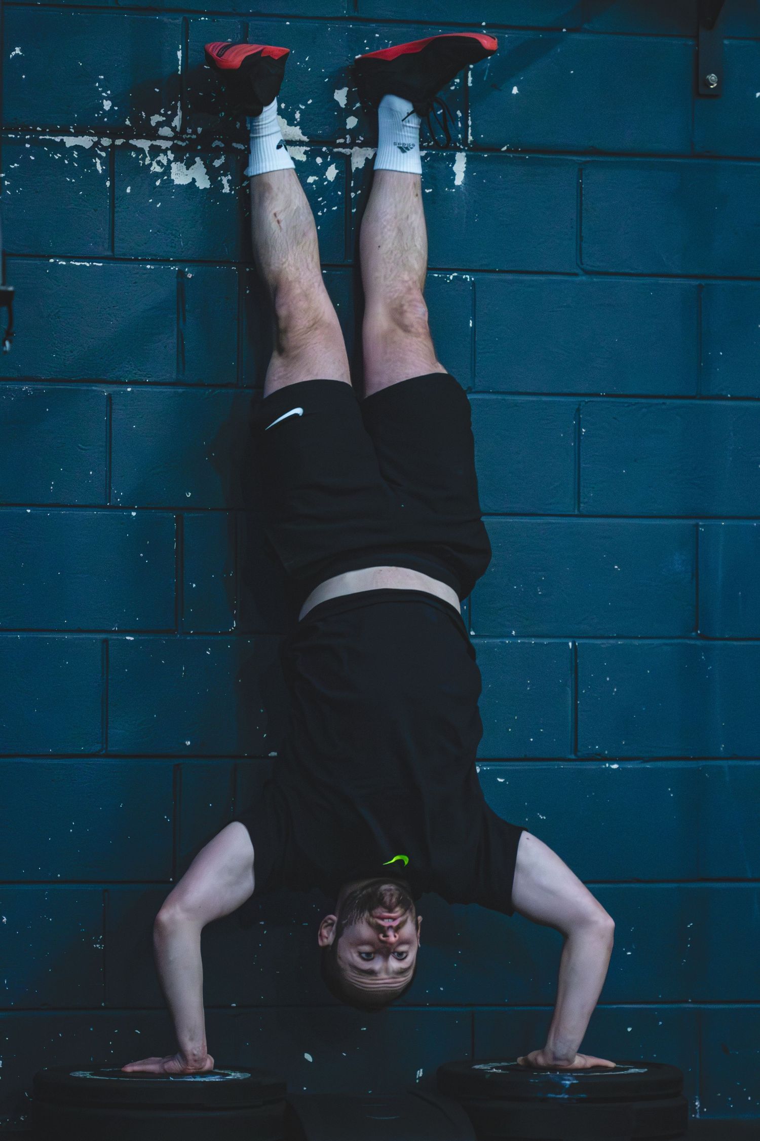 Legs in black pants standing against a turquoise blue wall creating a triptych-style artistic composition.