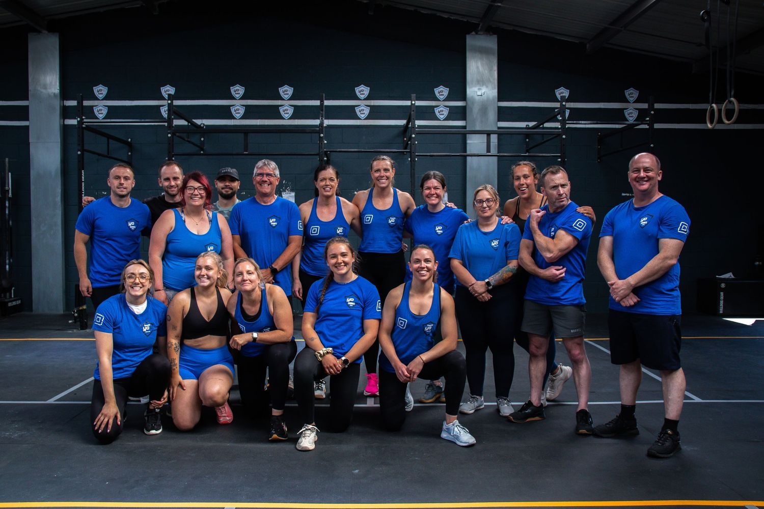 A panoramic view of athletes sitting together at a fitness facility in matching blue uniforms.