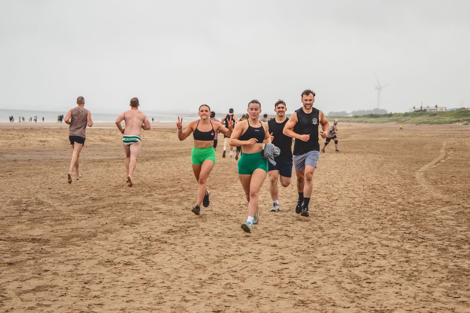 A group of runners racing across dry desert terrain during an outdoor competition event.