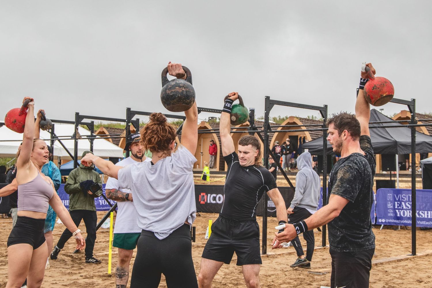 Athletes compete fiercely on an outdoor obstacle course with rope climbs and various challenges during a fitness competition.