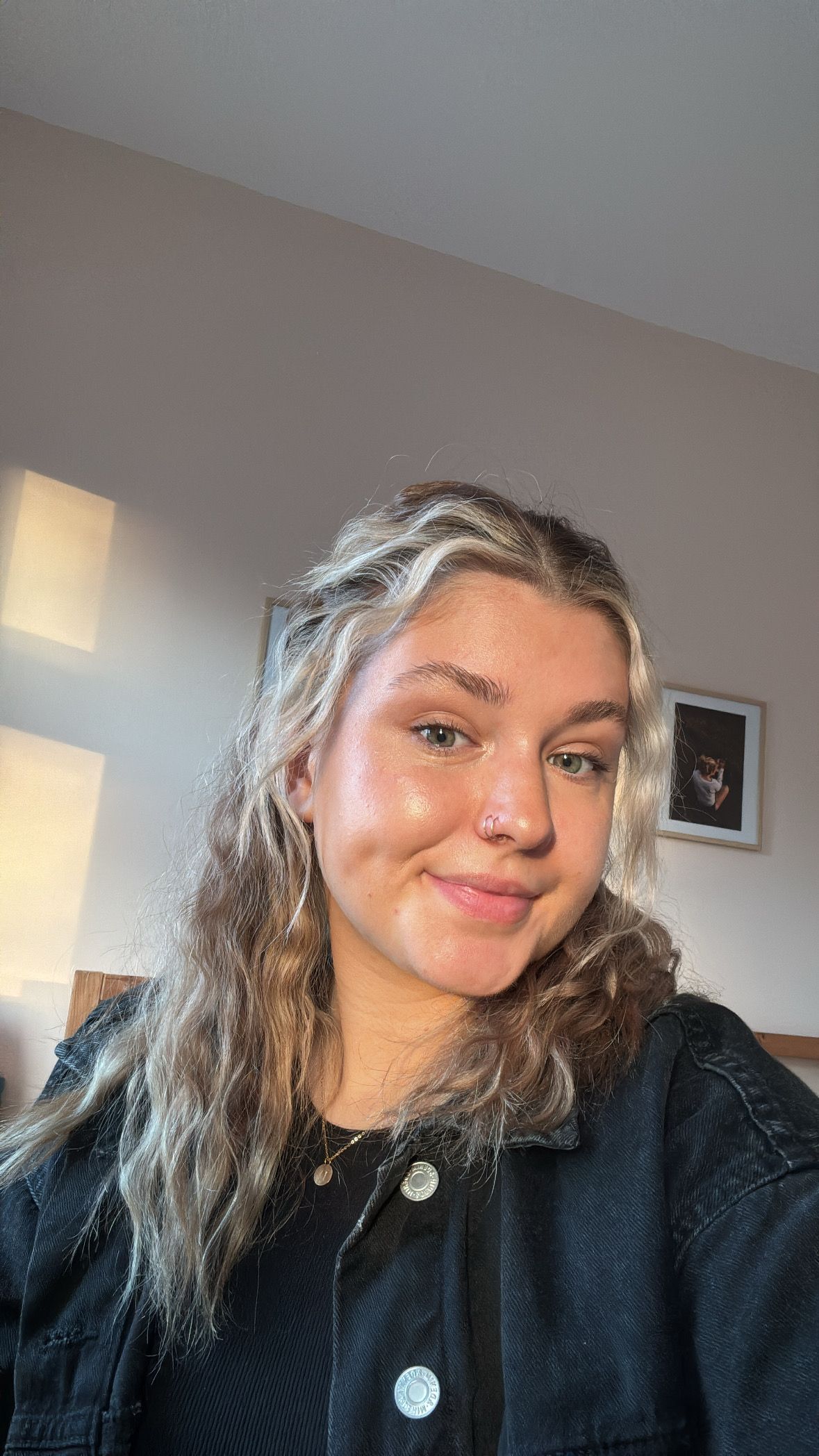 A selfie in natural lighting showing wavy blonde hair and a black denim jacket.