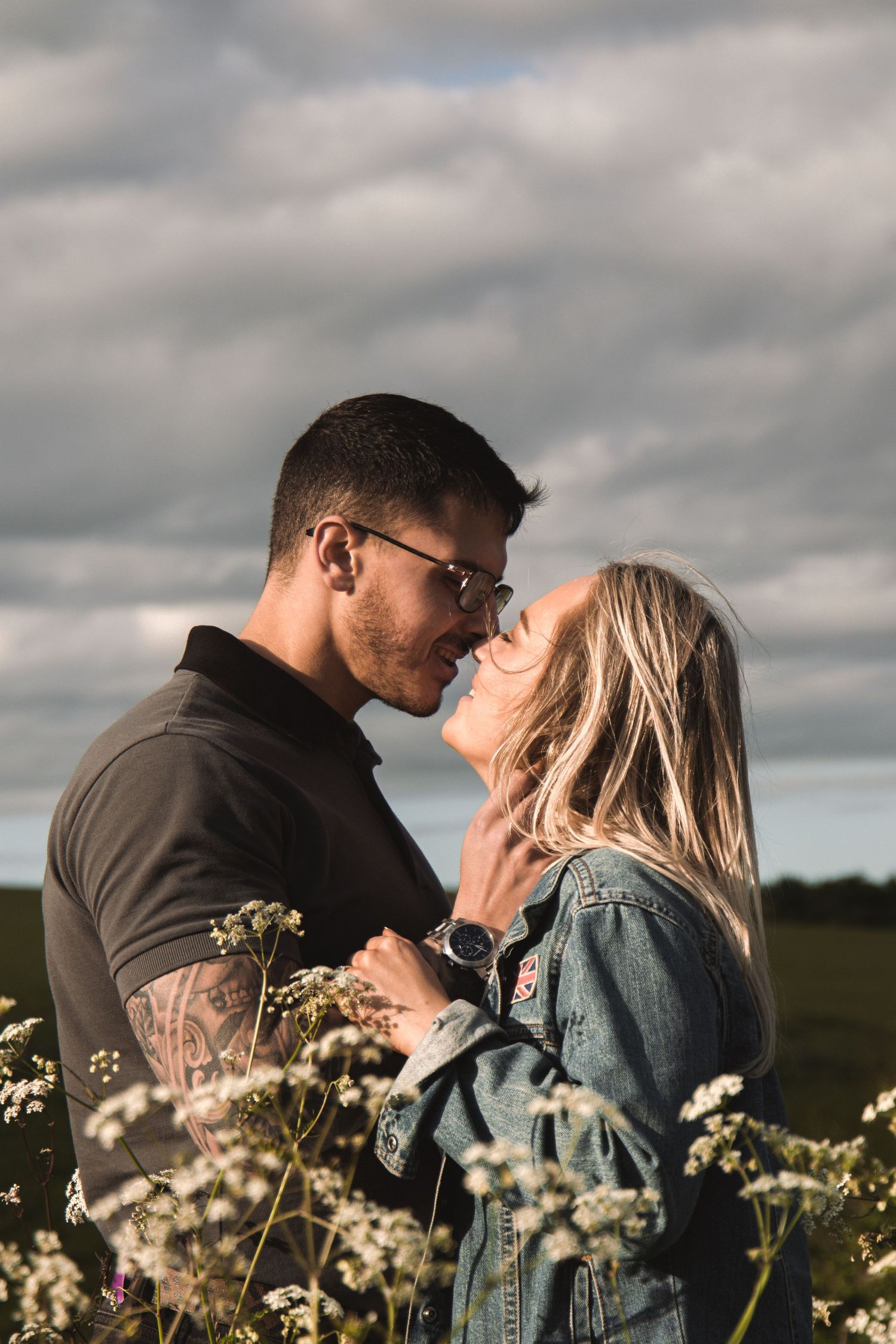 Intimate portrait of a couple about to kiss among wildflowers at sunset.