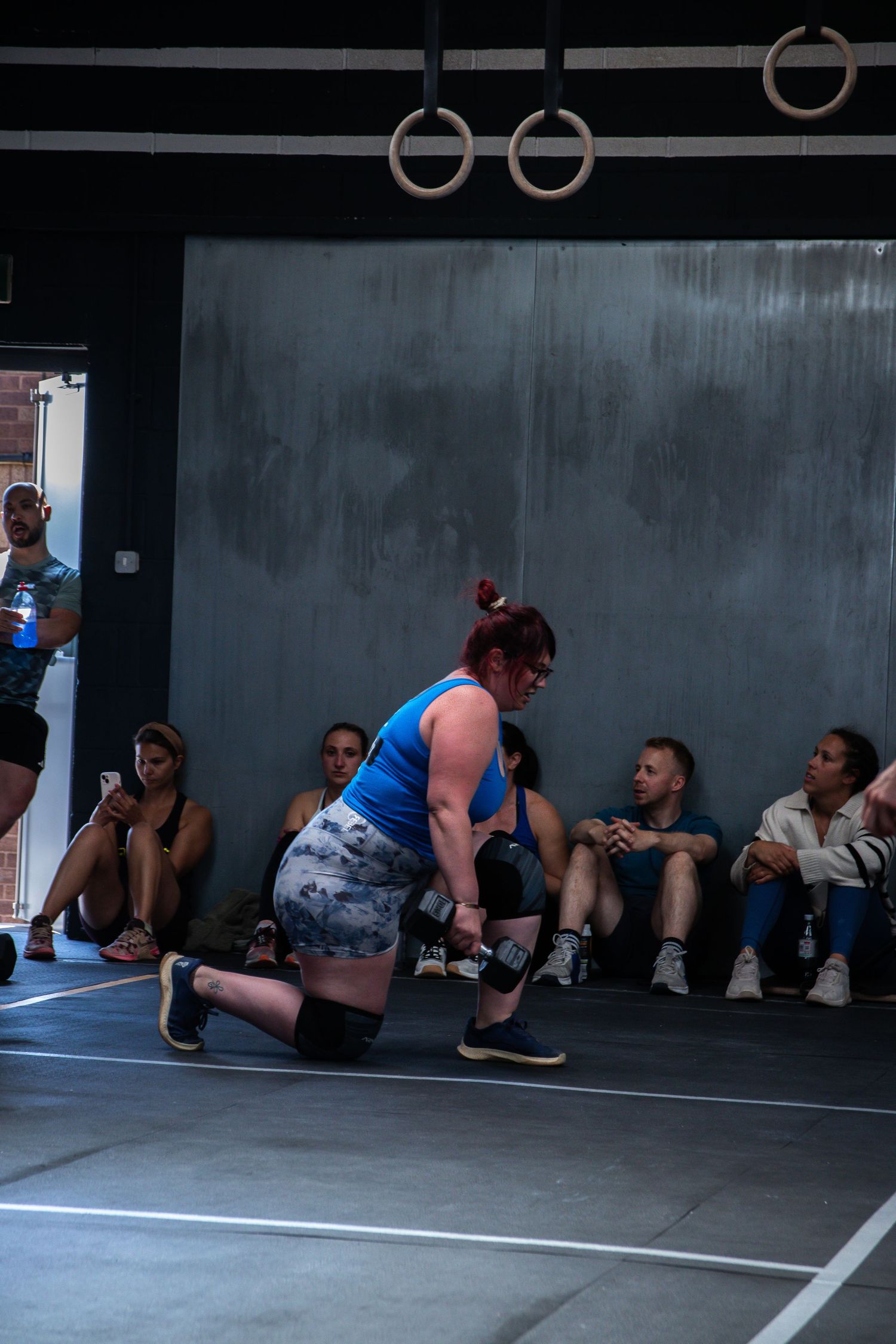 Athletes performing stretching exercises along a wall during a group fitness class at a CrossFit gym.