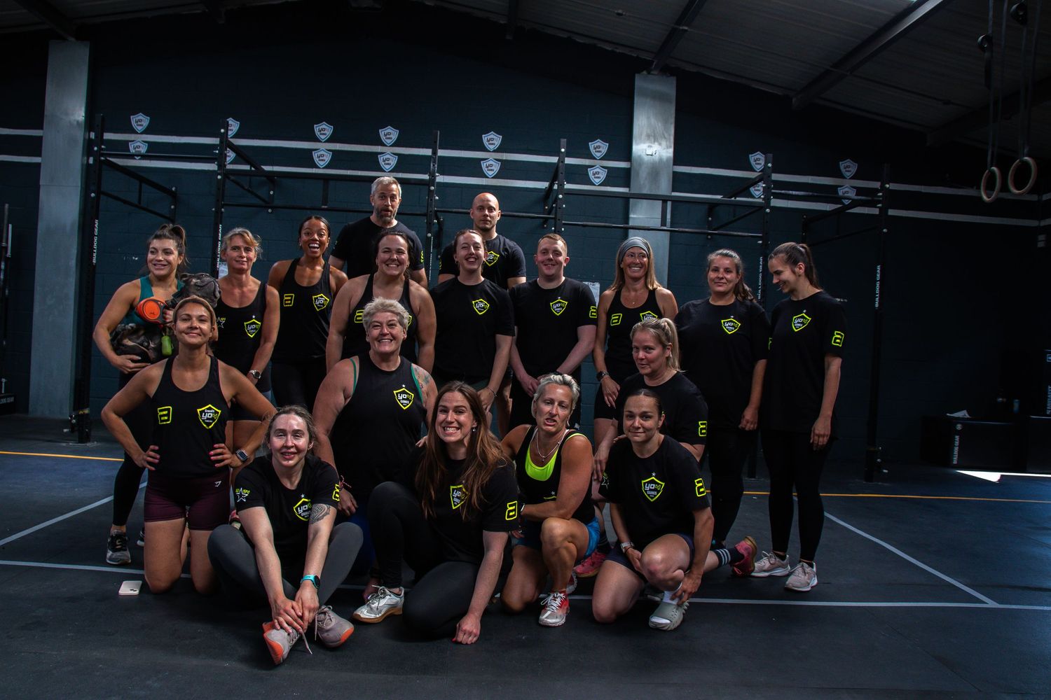 A group of cheerleaders posing together in black uniforms after a performance on a basketball court.