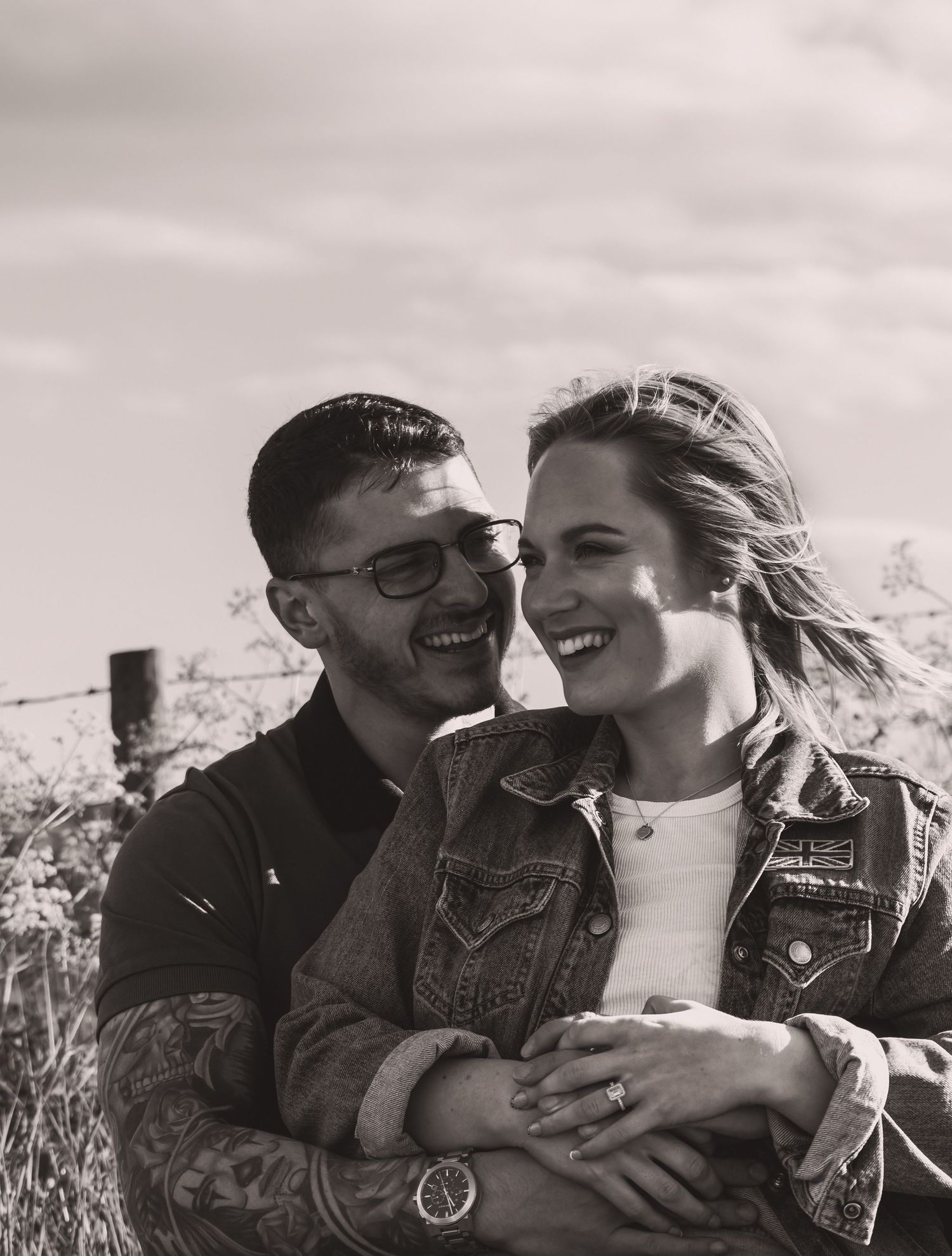 Black and white candid shot of couple sharing joyful moments outdoors.