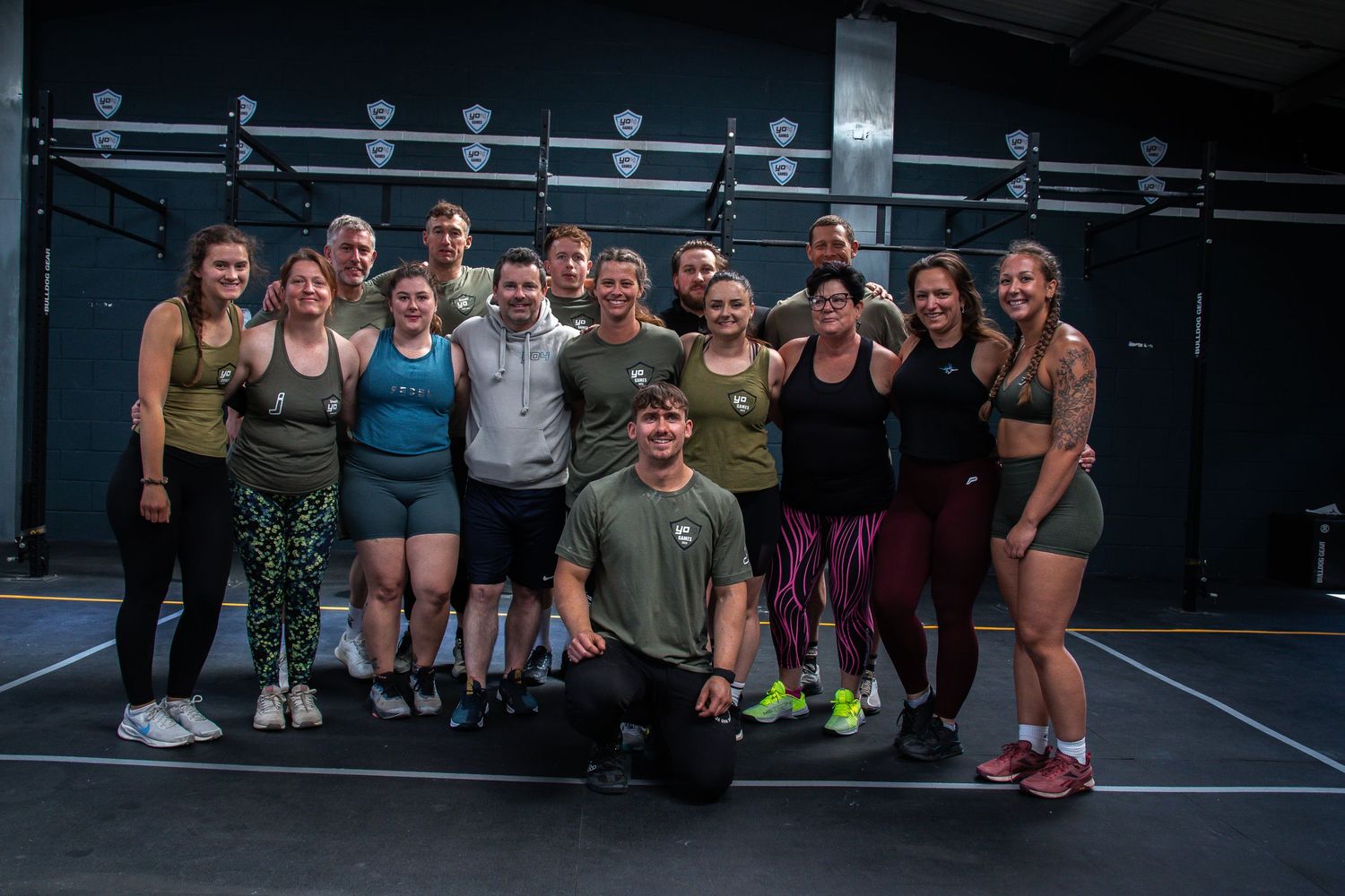A large group of fitness enthusiasts gather together after a workout at a CrossFit style gym facility.