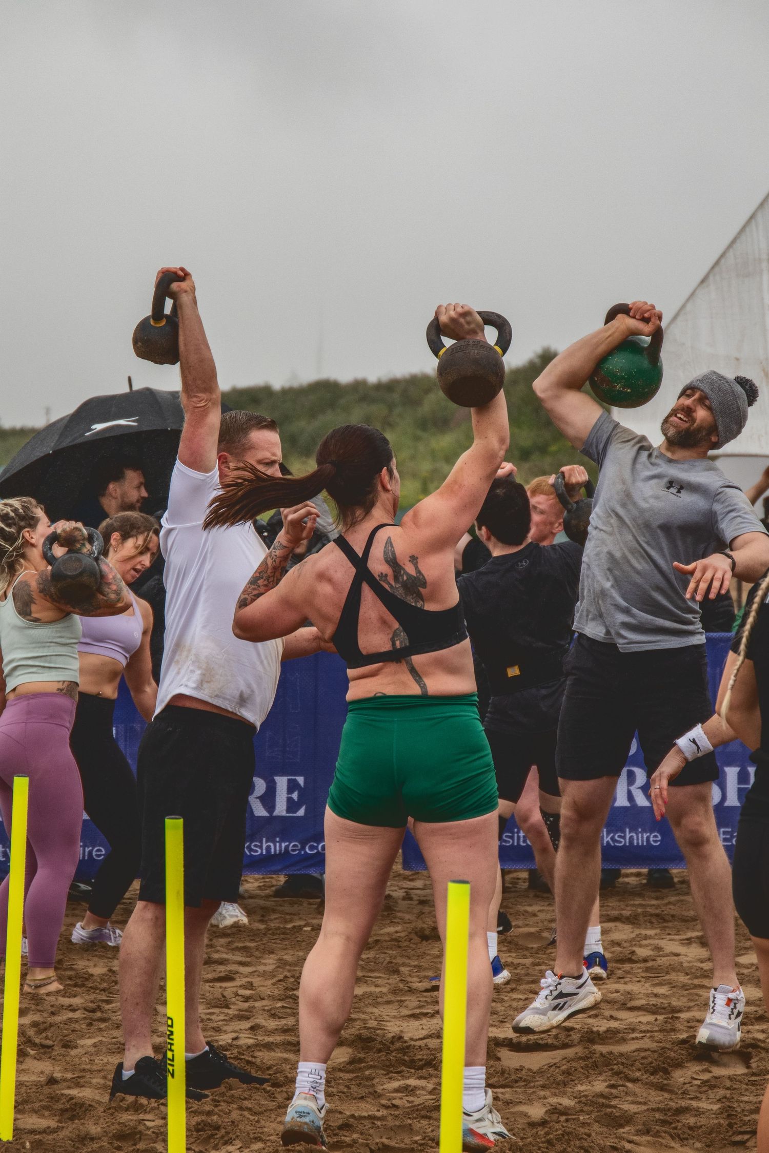 A sequence of photos showing athletes drinking from bottles while training outdoors near the beach during a group exercise class.