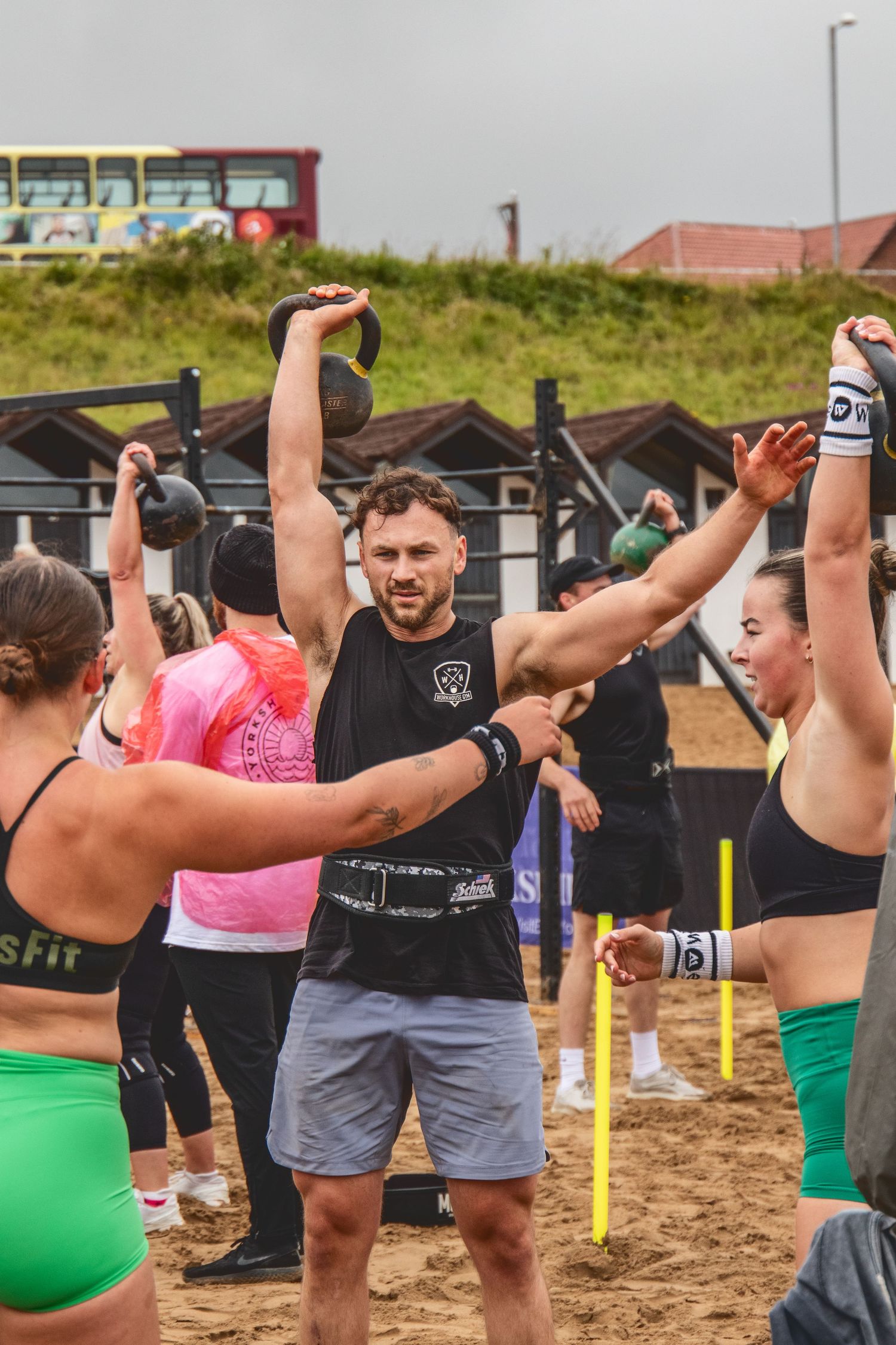 Athletes perform synchronized training exercises with resistance bands on a beach during an outdoor fitness class.