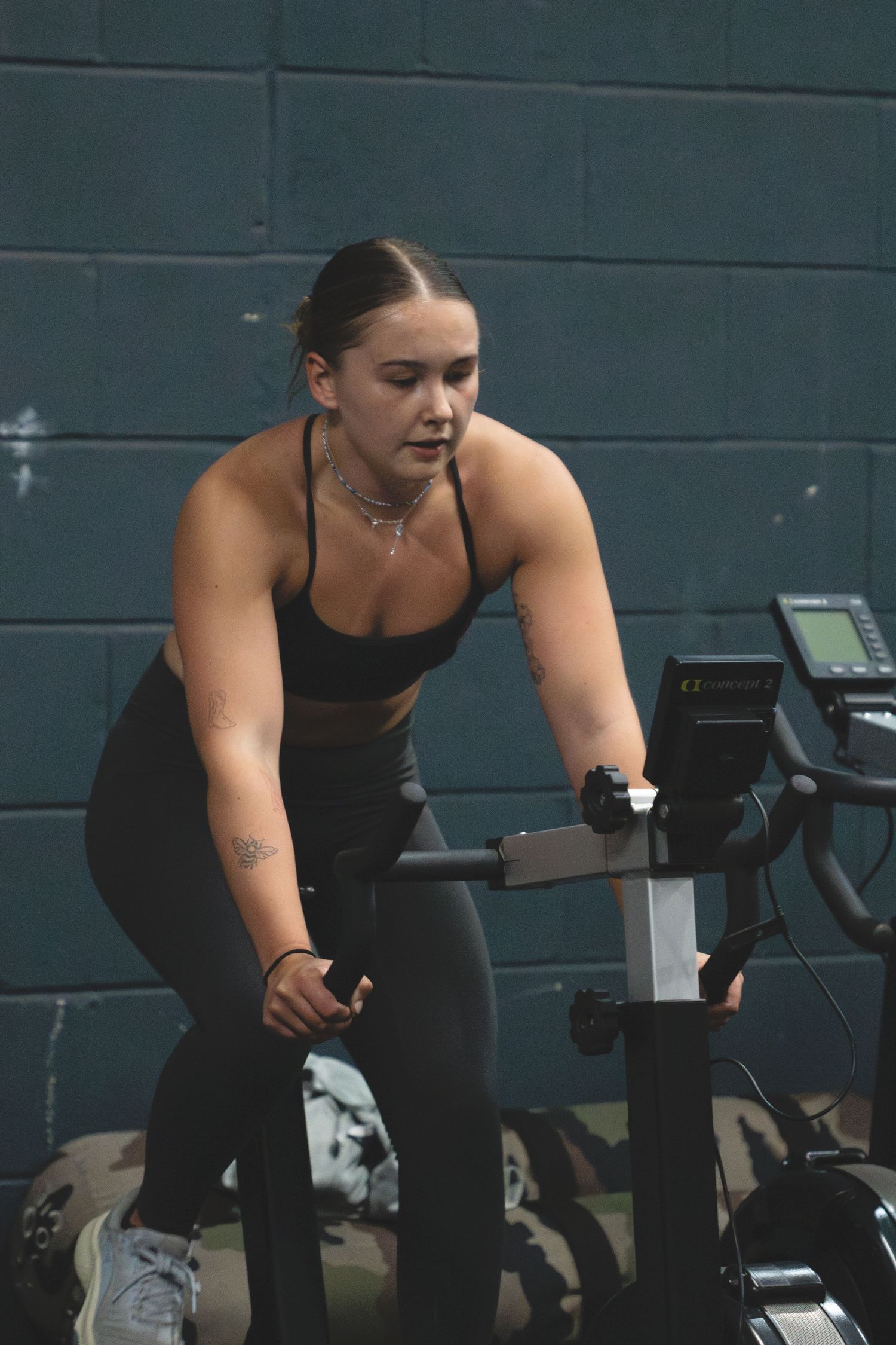 Person exercising on a stationary bike during an indoor workout session against a dark wall.
