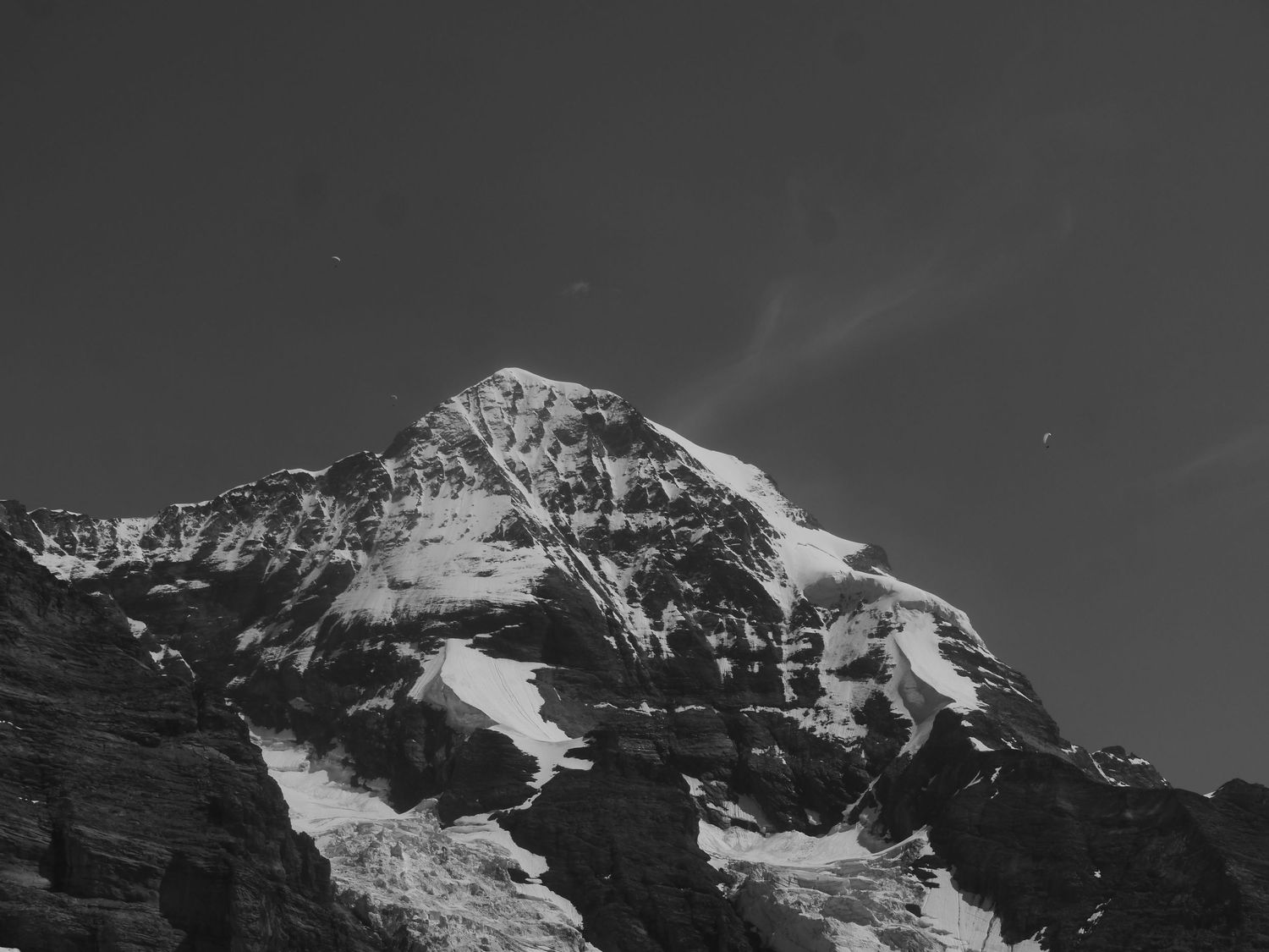 Black and white mountain peak covered in snow against a dramatic sky.