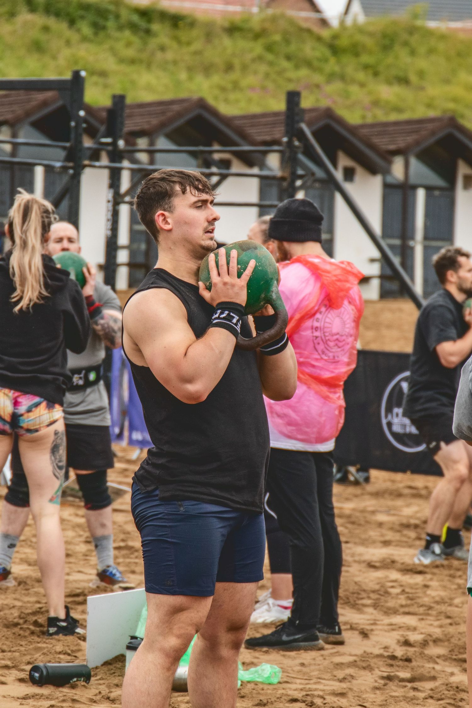 Athletes perform exercises during an outdoor CrossFit workout session with beach huts in the background.